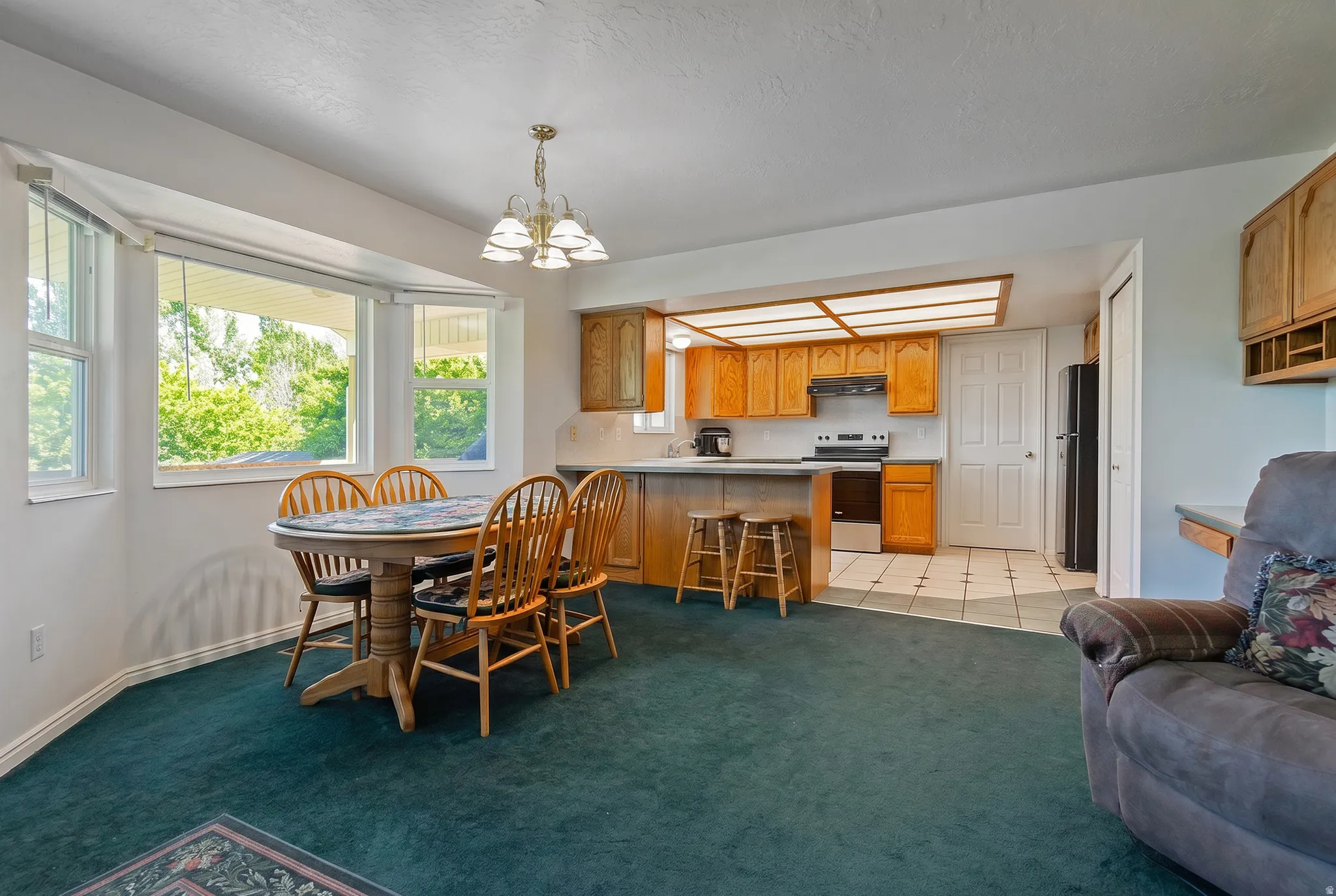 Bright dining area featuring a bay window, a breakfast bar, and a kitchen with wood cabinetry