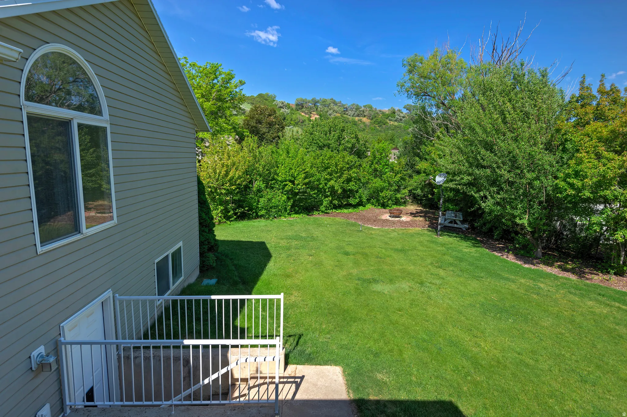 Expansive green lawn with mature trees and a dedicated fire pit area