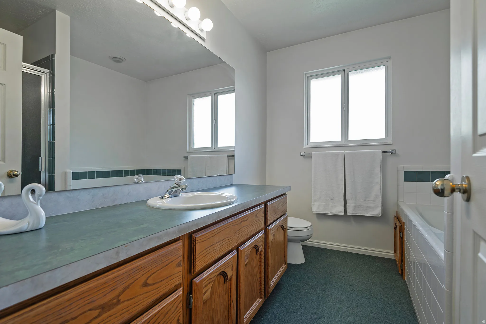 Bathroom featuring a wide vanity with a single basin, wood cabinetry, and a full-width mirror