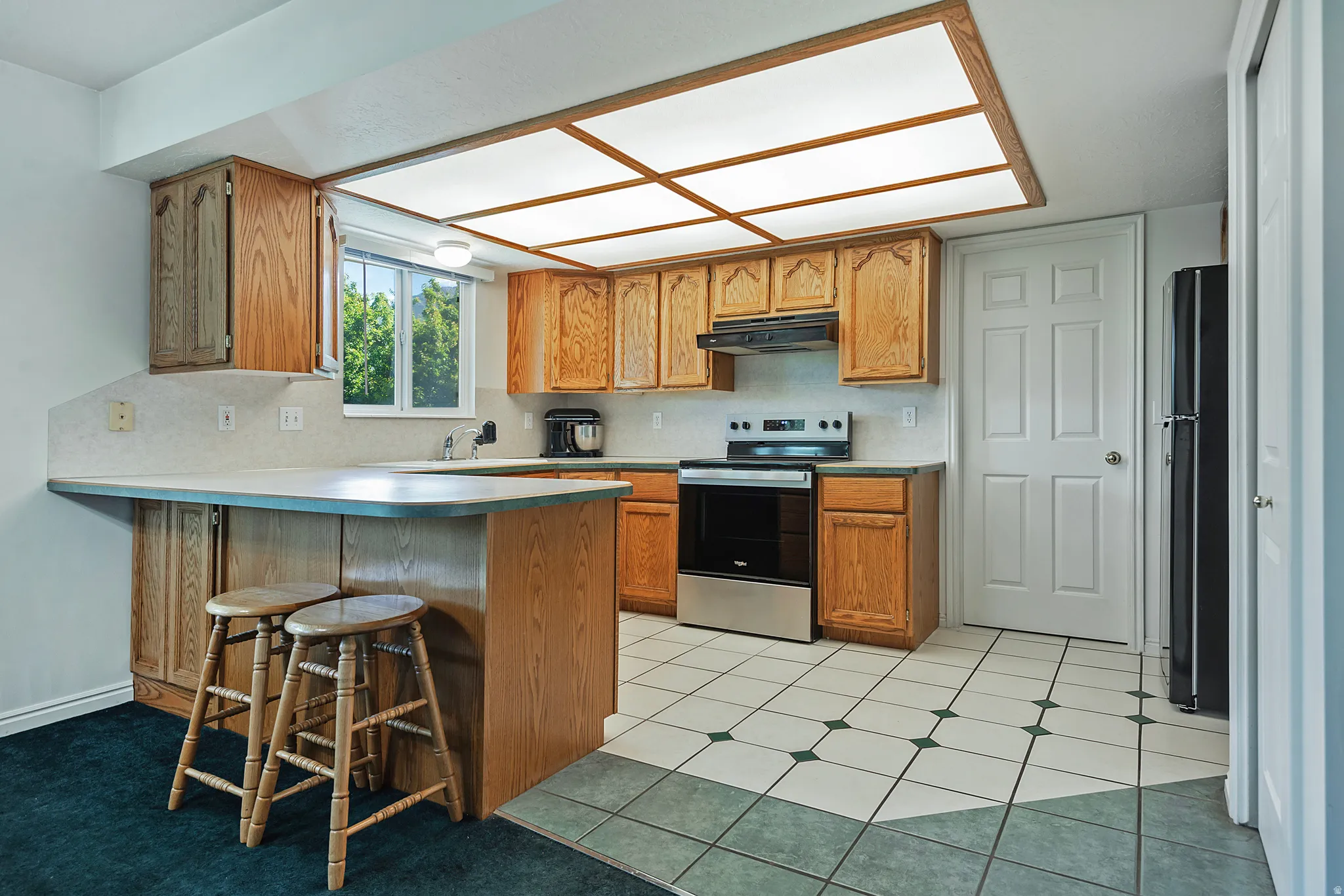 Kitchen featuring oak cabinetry, a white tile backsplash, and a breakfast bar