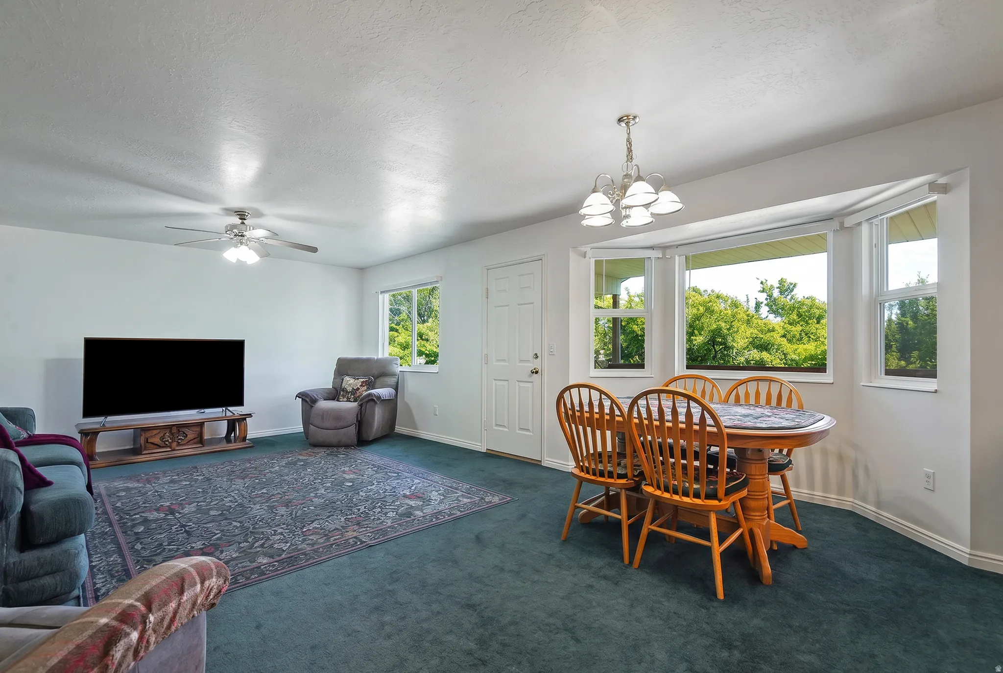 Open living space featuring a ceiling fan, bay window, and a built-in lighting fixture