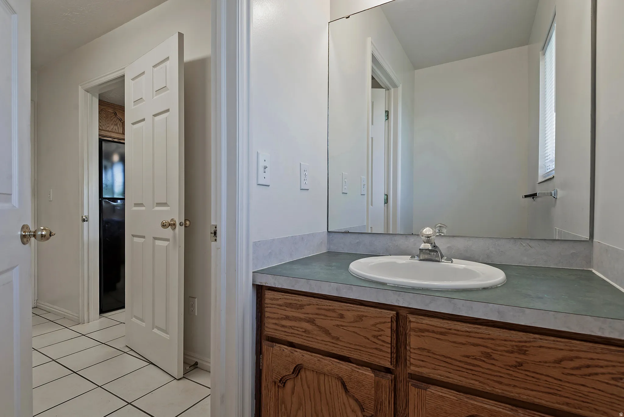 Vanity with an integrated oval sink, laminate countertop, and wood-finish cabinetry