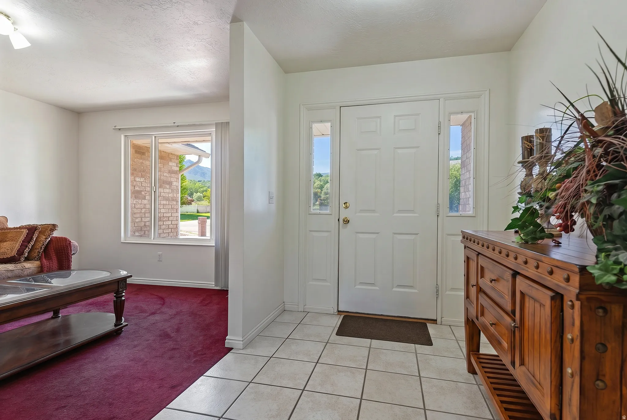 Entryway featuring white panel door with sidelights, ceramic tile flooring, and a window providing natural illumination