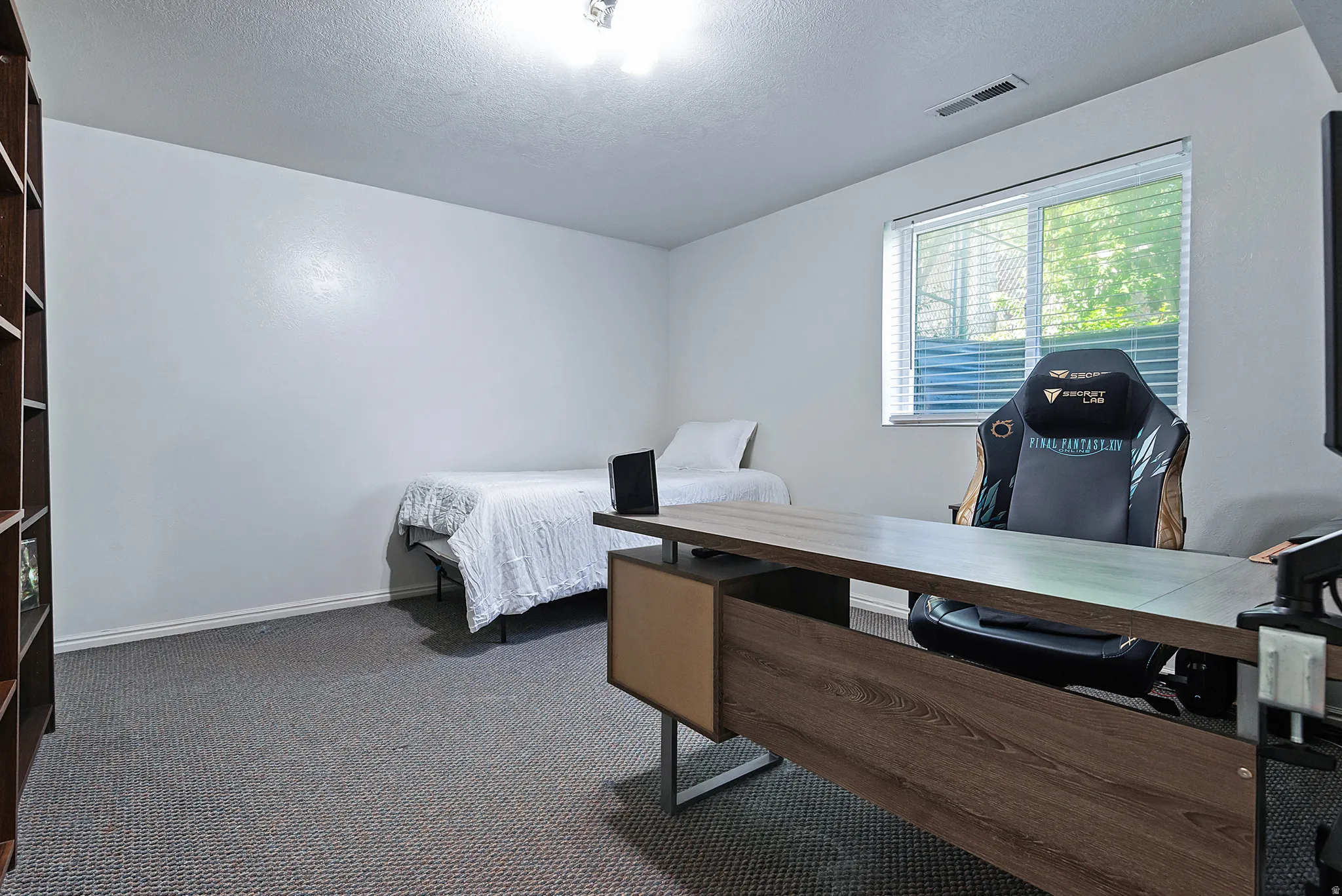 Carpeted room with a built-in wood-finish shelving unit, a window with horizontal blinds, and recessed lighting