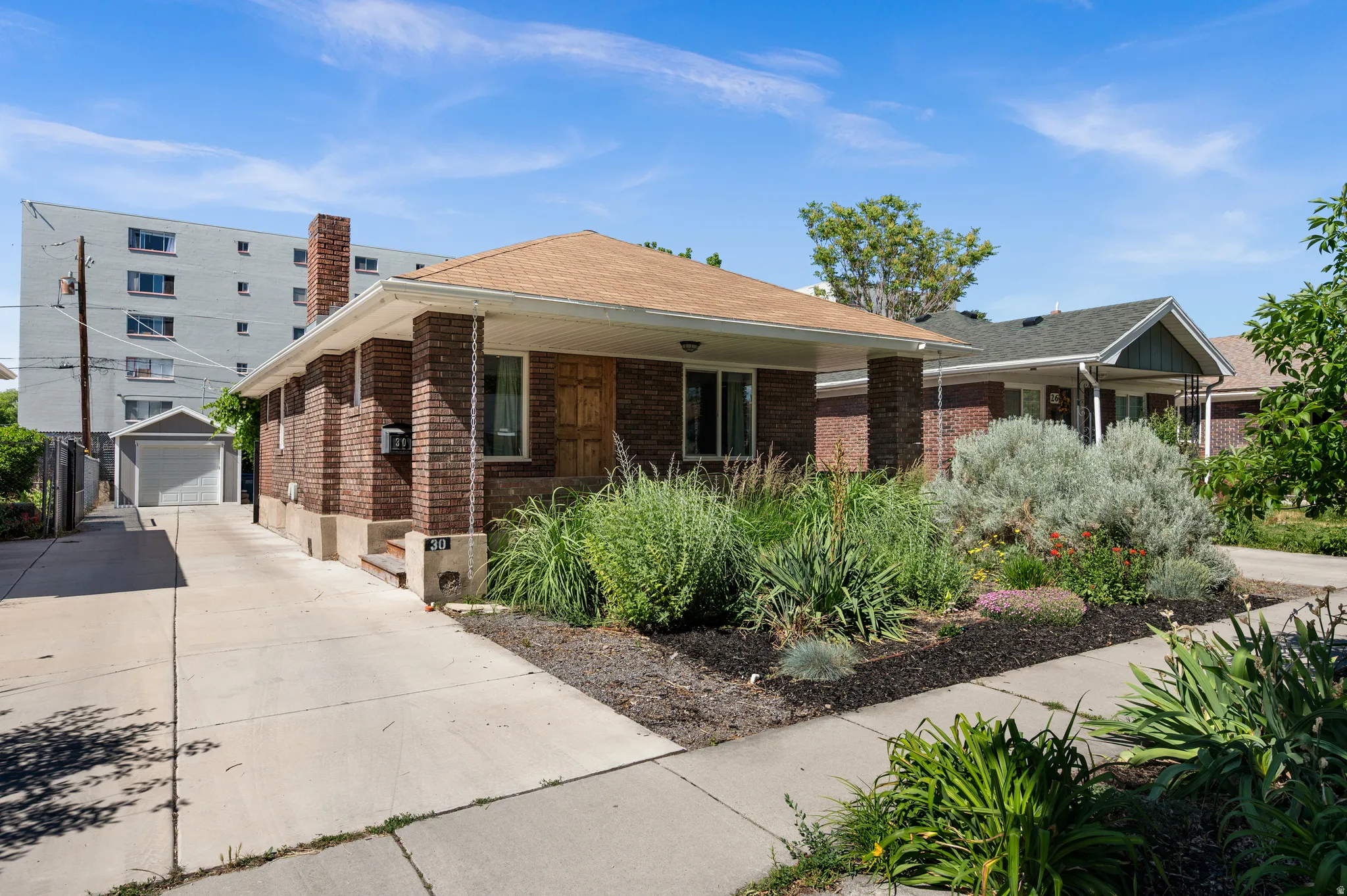 Brick bungalow with xeriscaped front yard, single-car detached garage