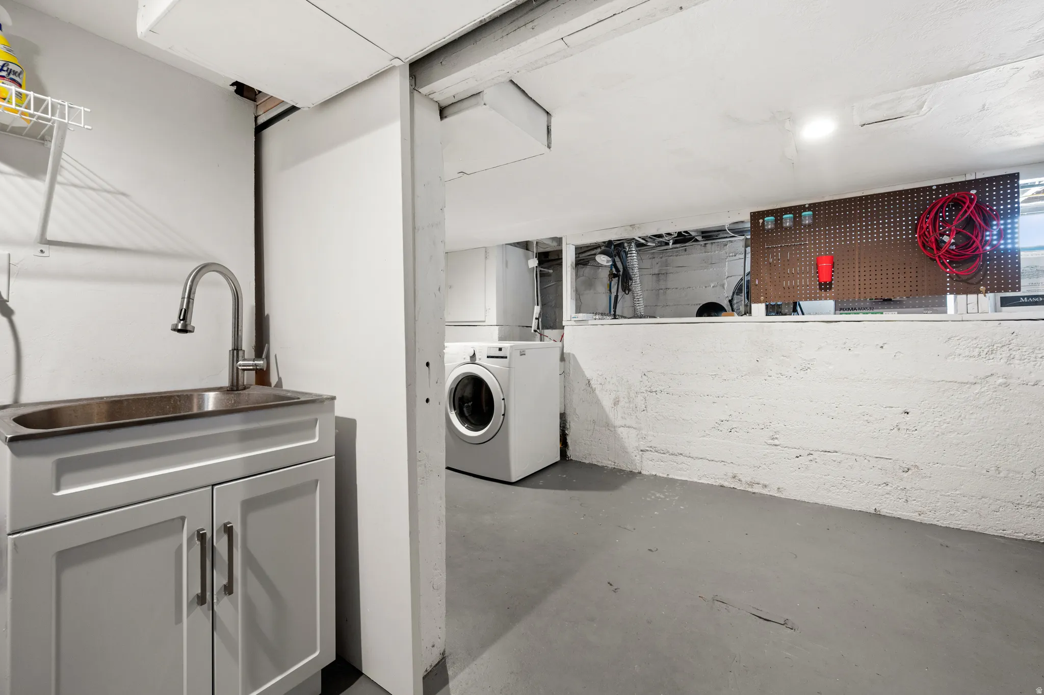 Dedicated utility area featuring a stainless steel sink with a high-arc faucet,  and laundry appliances