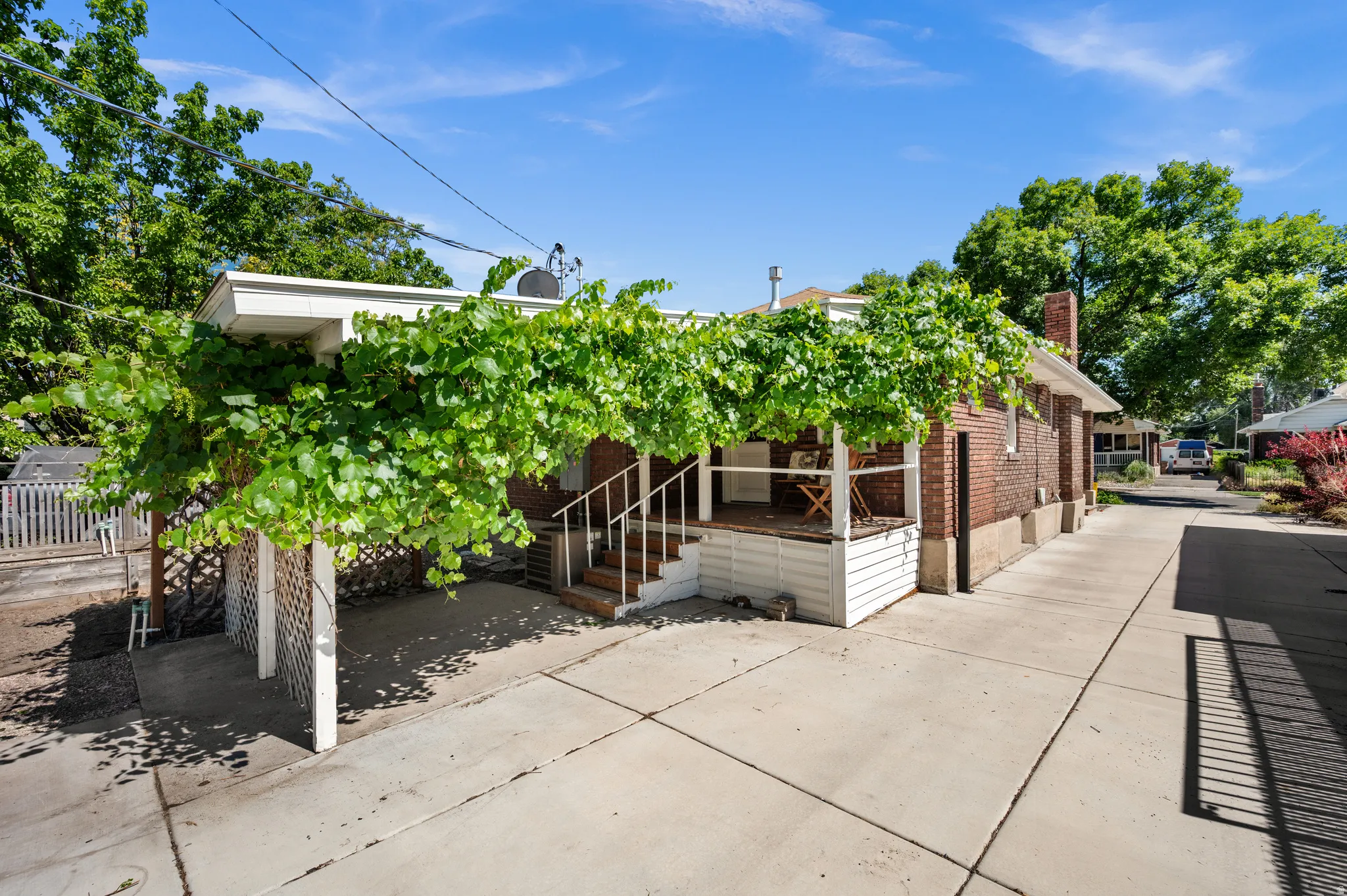Newer concrete driveway, covered deck and patio with an overhead trellis with grapevine