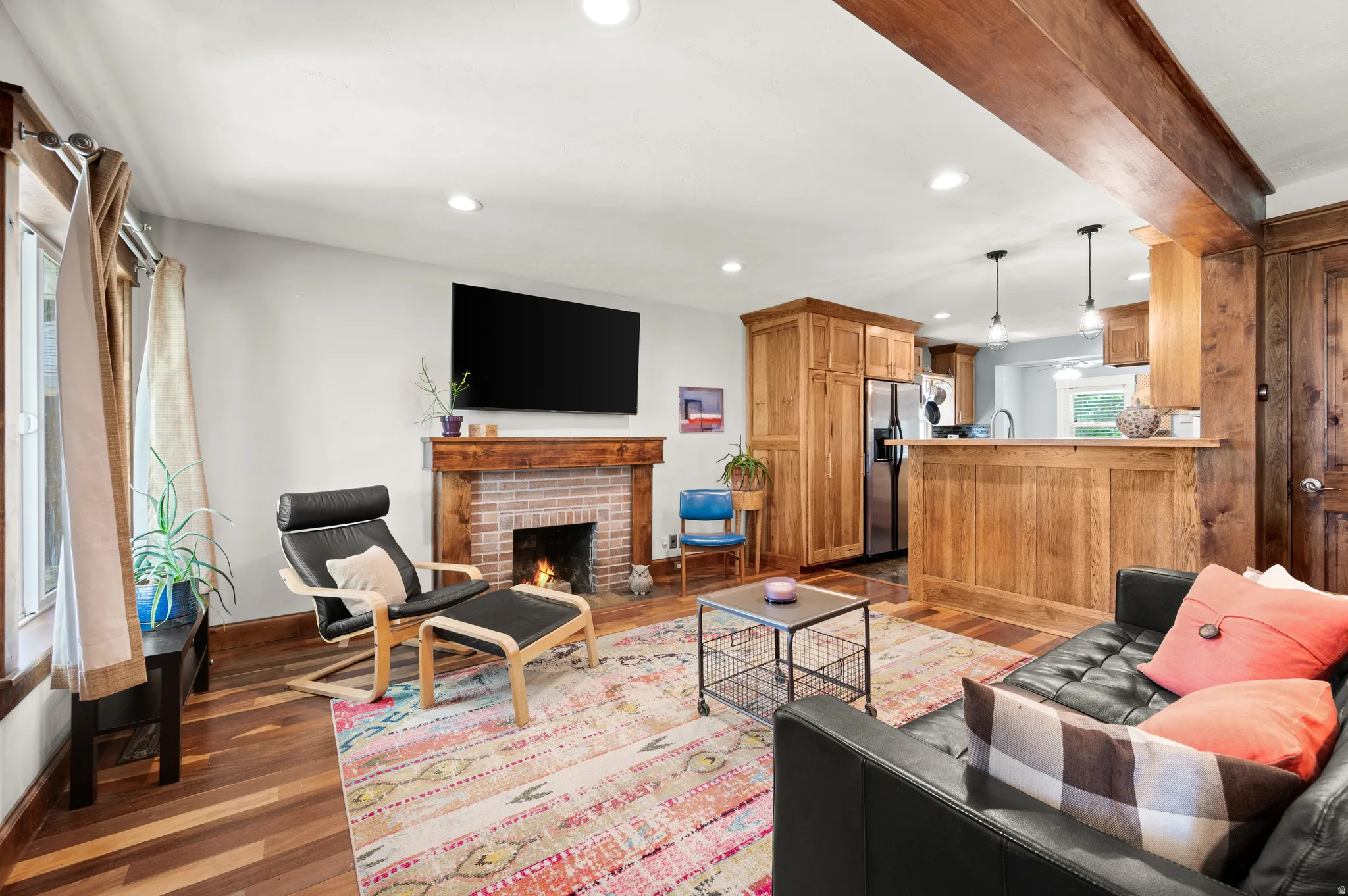 Living room featuring a brick fireplace with a wood mantle, wood flooring, recessed lighting and open to the remodeled kitchen