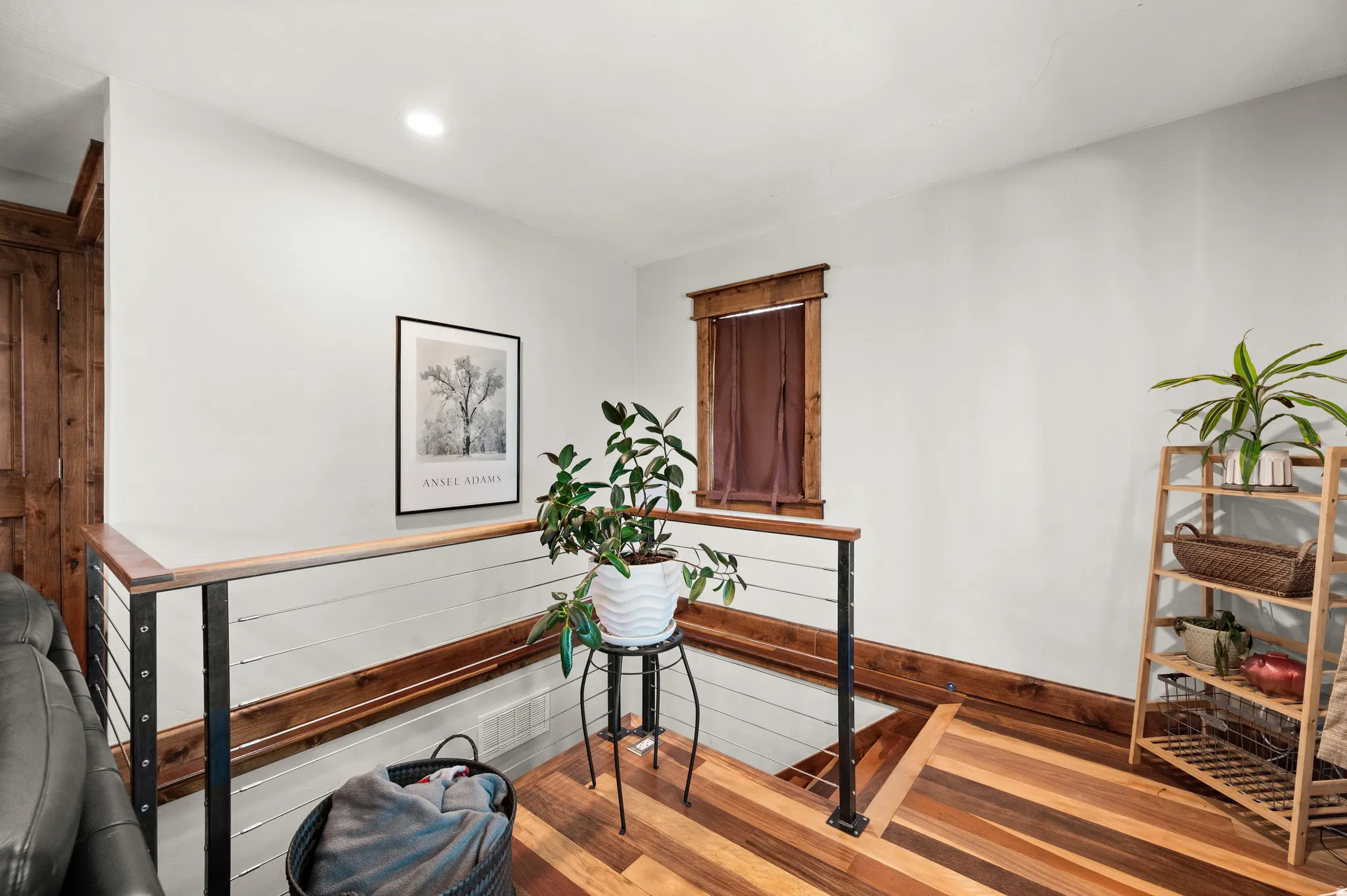 Stairs to basement with decorative cable railing system, recessed lighting, and a wood-trimmed window