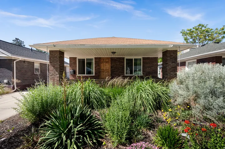 Brick Bungalow with covered front porch and mature xeriscaped front yard with drip system