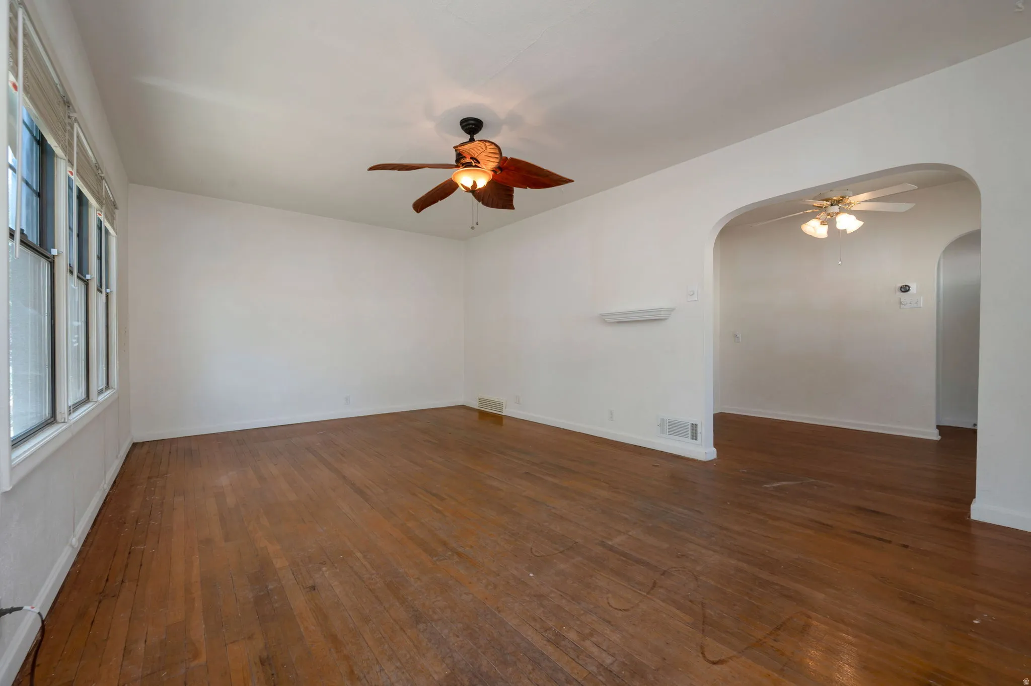 Spacious interior featuring wood-finish flooring, white walls, and a ceiling fan