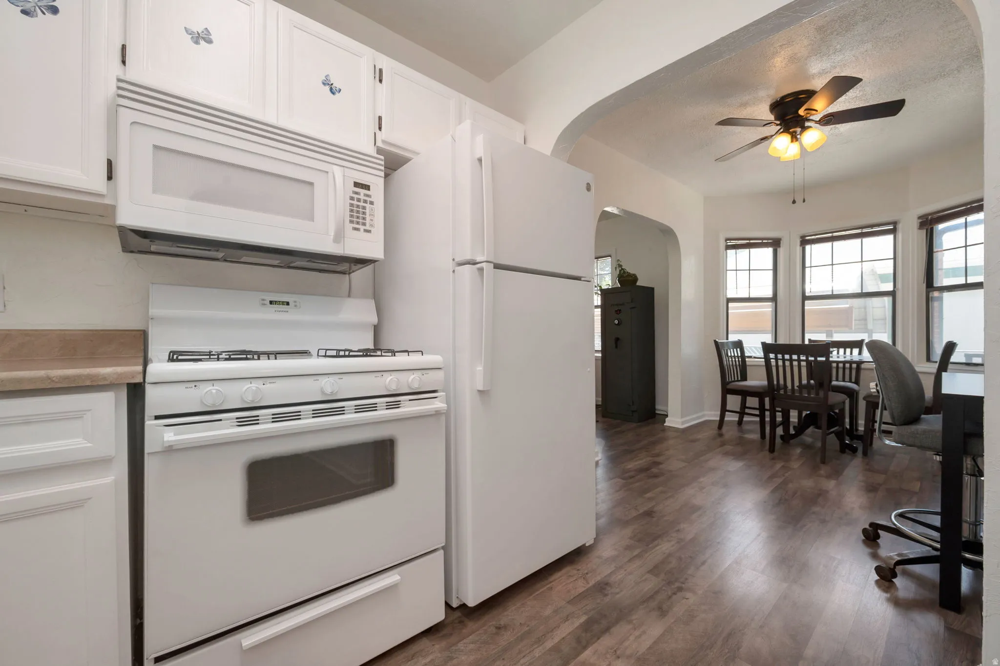 Kitchen area featuring white cabinetry, white appliances, and wood-finish flooring