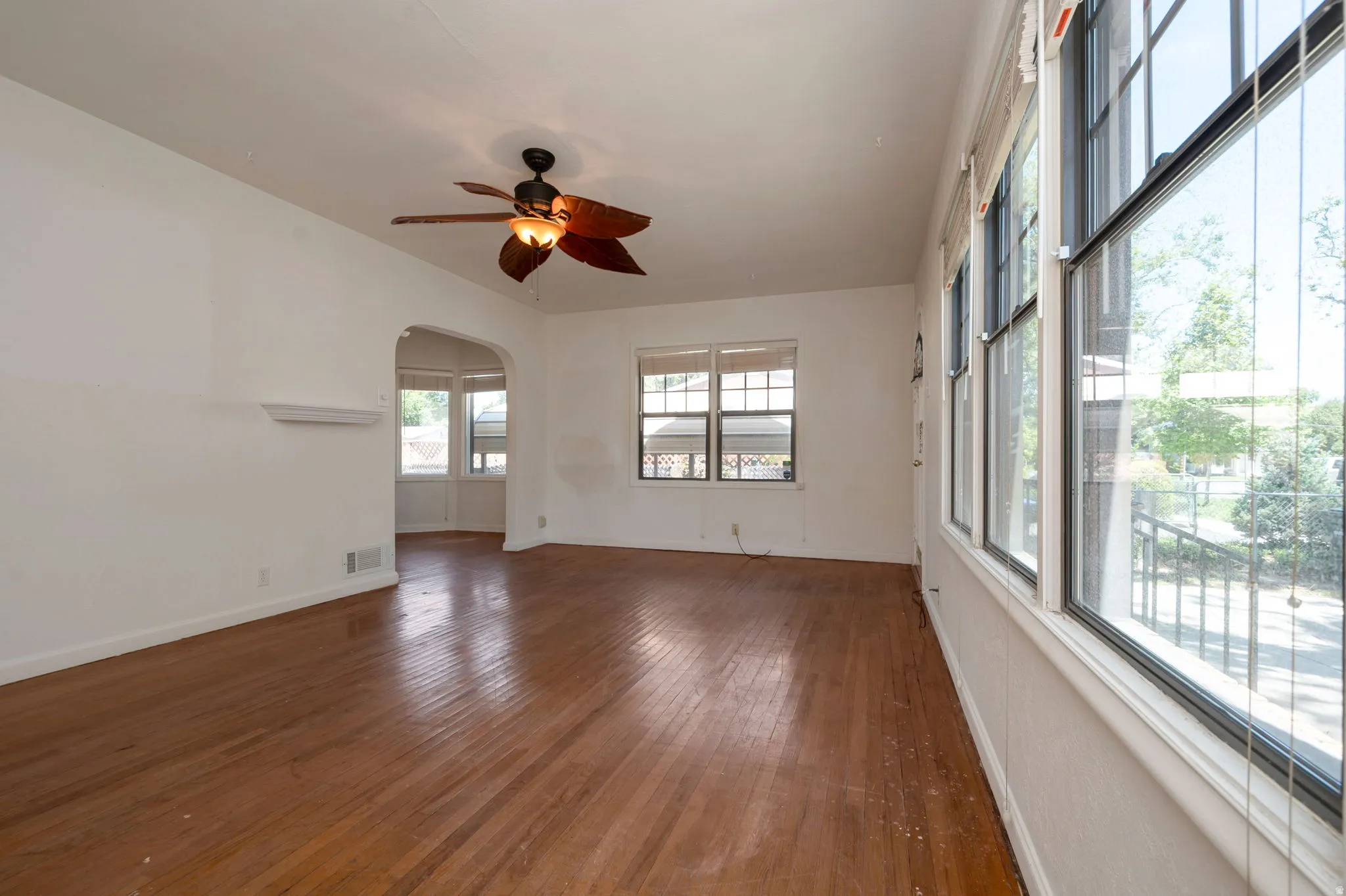 Hardwood flooring extending throughout, complemented by a ceiling fan with integrated lighting