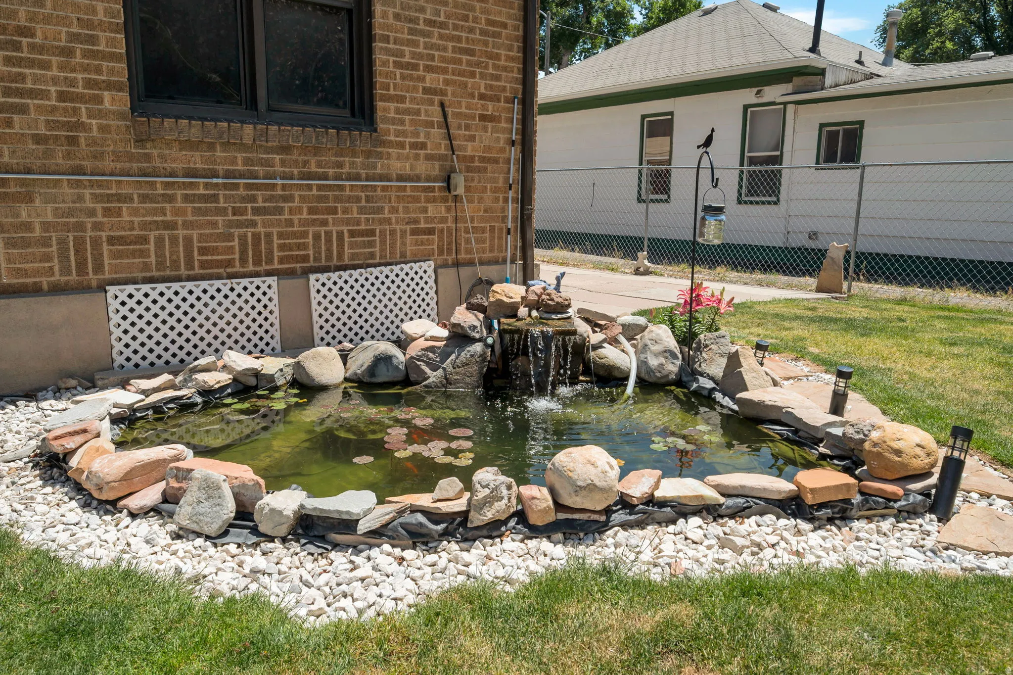Landscaped rock pond with waterfall feature, surrounded by white decorative gravel