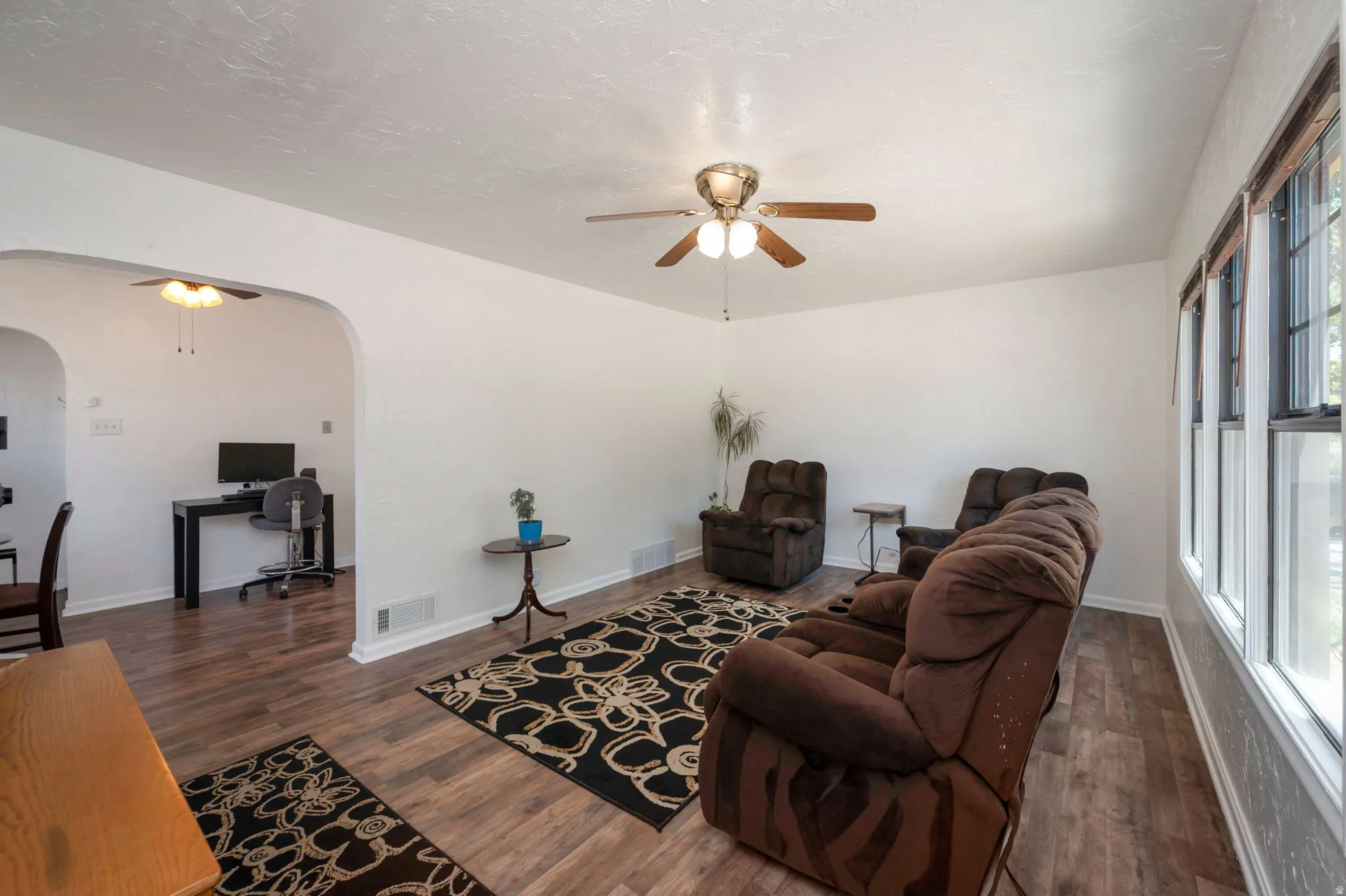 Spacious interior featuring wood-finish flooring, white walls, and multiple windows with wood blinds