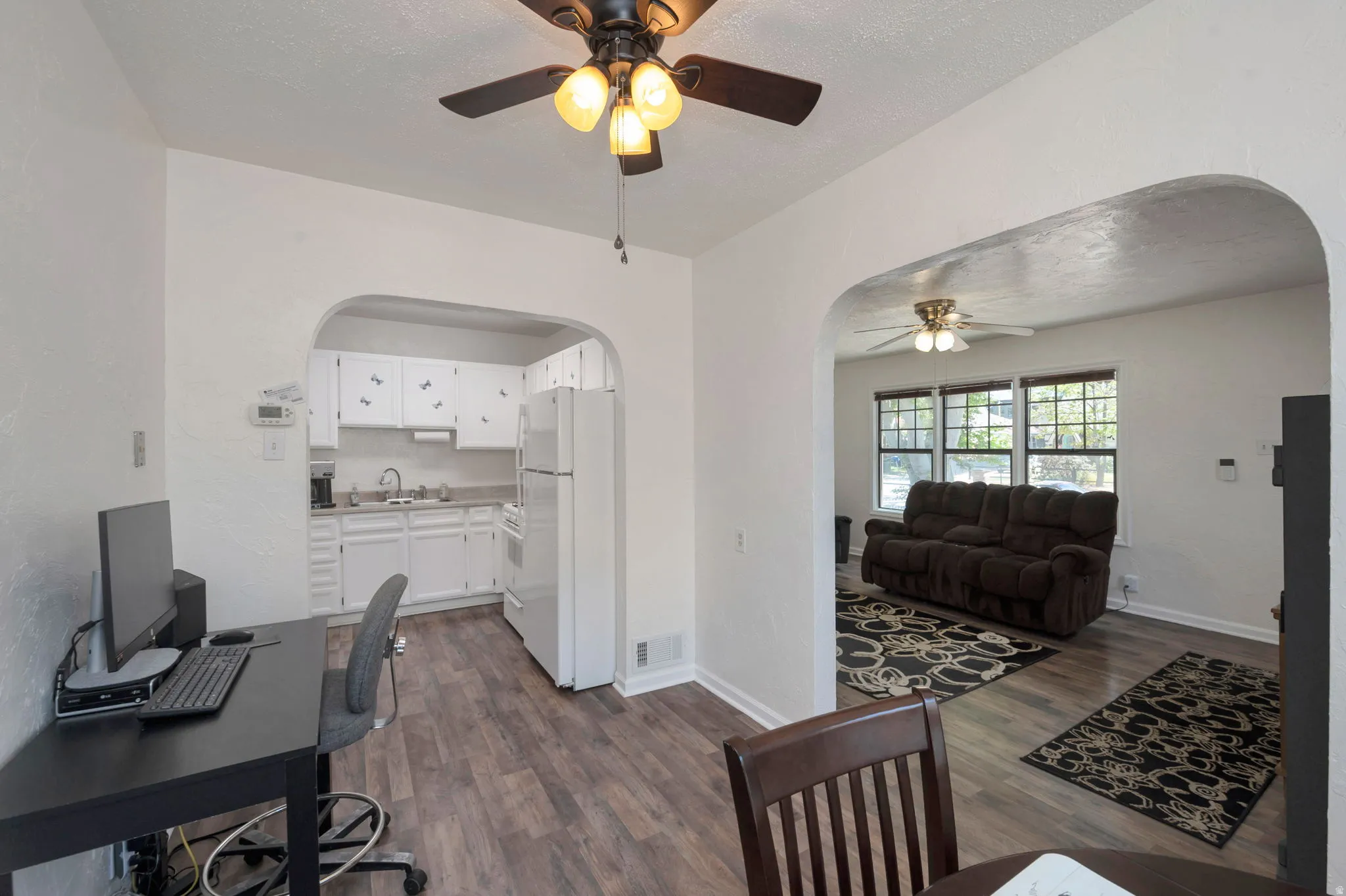 Open-concept living space featuring wood-finish flooring, white walls, and a ceiling fan