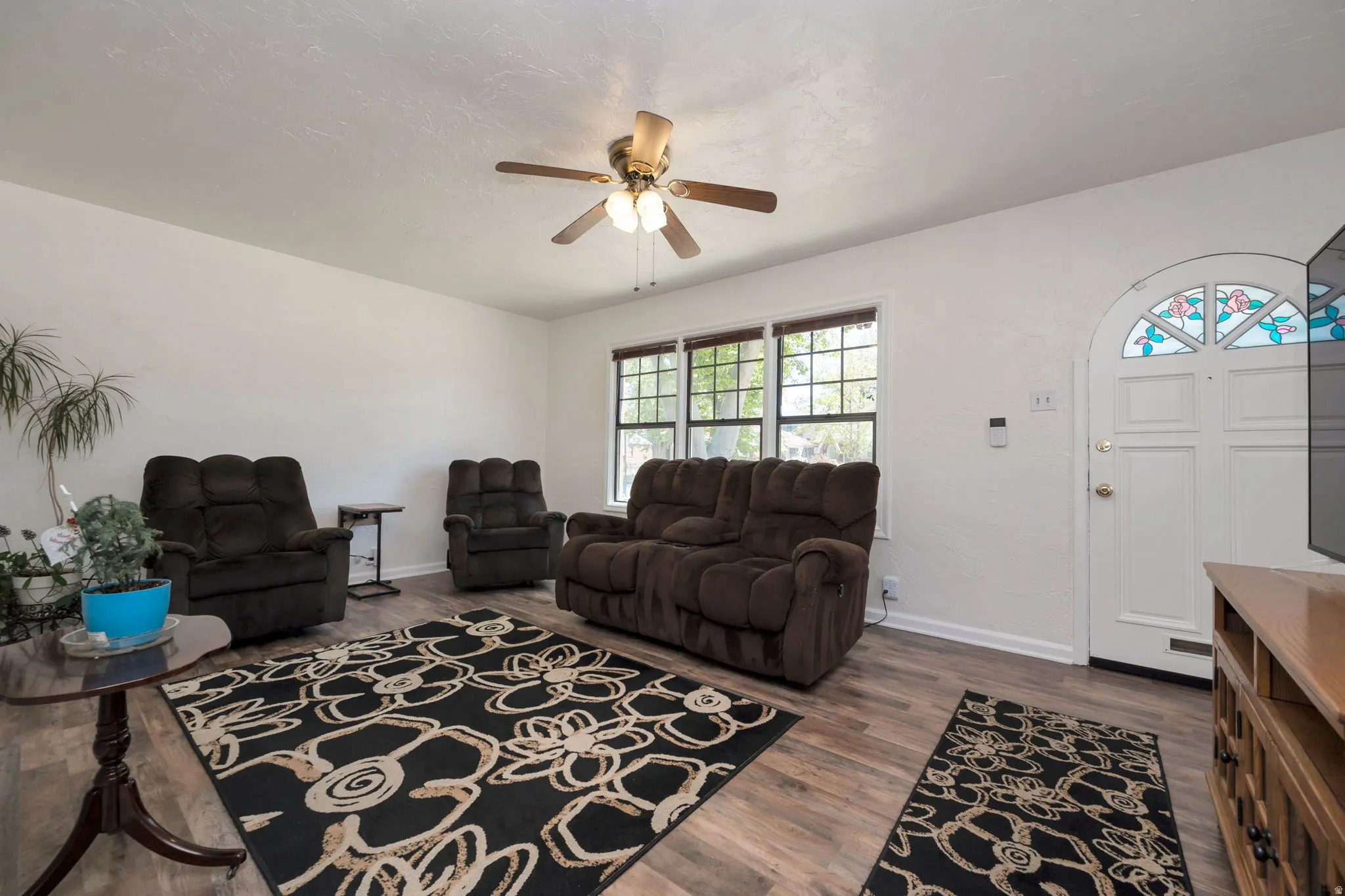 Living area featuring wood-finish flooring, white walls, and a decorative arched entry door with stained glass