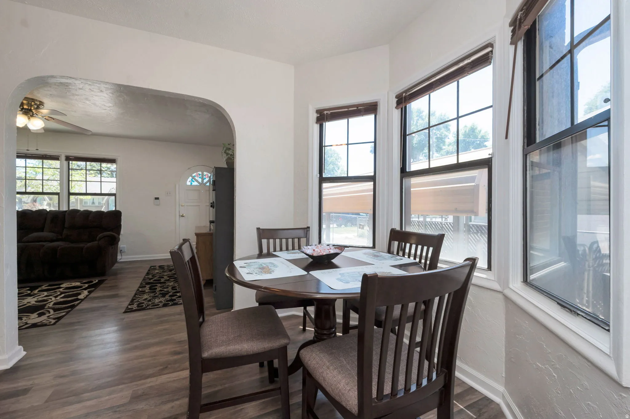Bay window dining area featuring multiple windows, wood-finish flooring, and an arched doorway opening to an additional living space