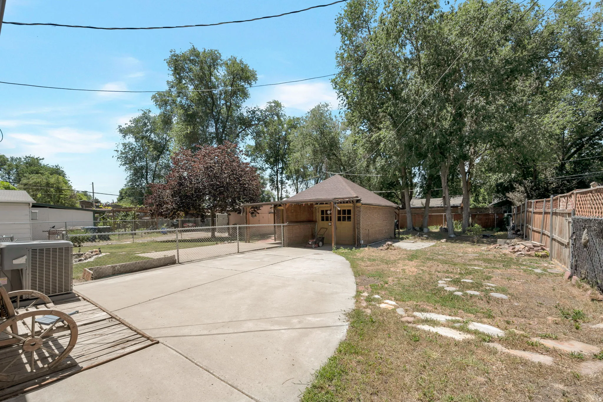 Expansive concrete patio area with a chain-link fence defining a grassy yard space