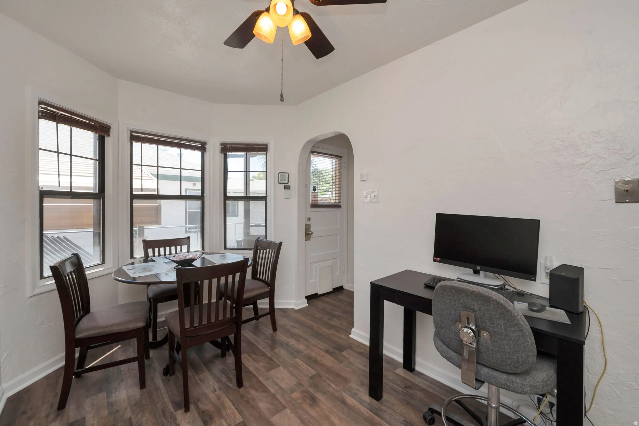 Dining area featuring wood-finish flooring, a bay window with multiple panes, and a ceiling fan with light fixture