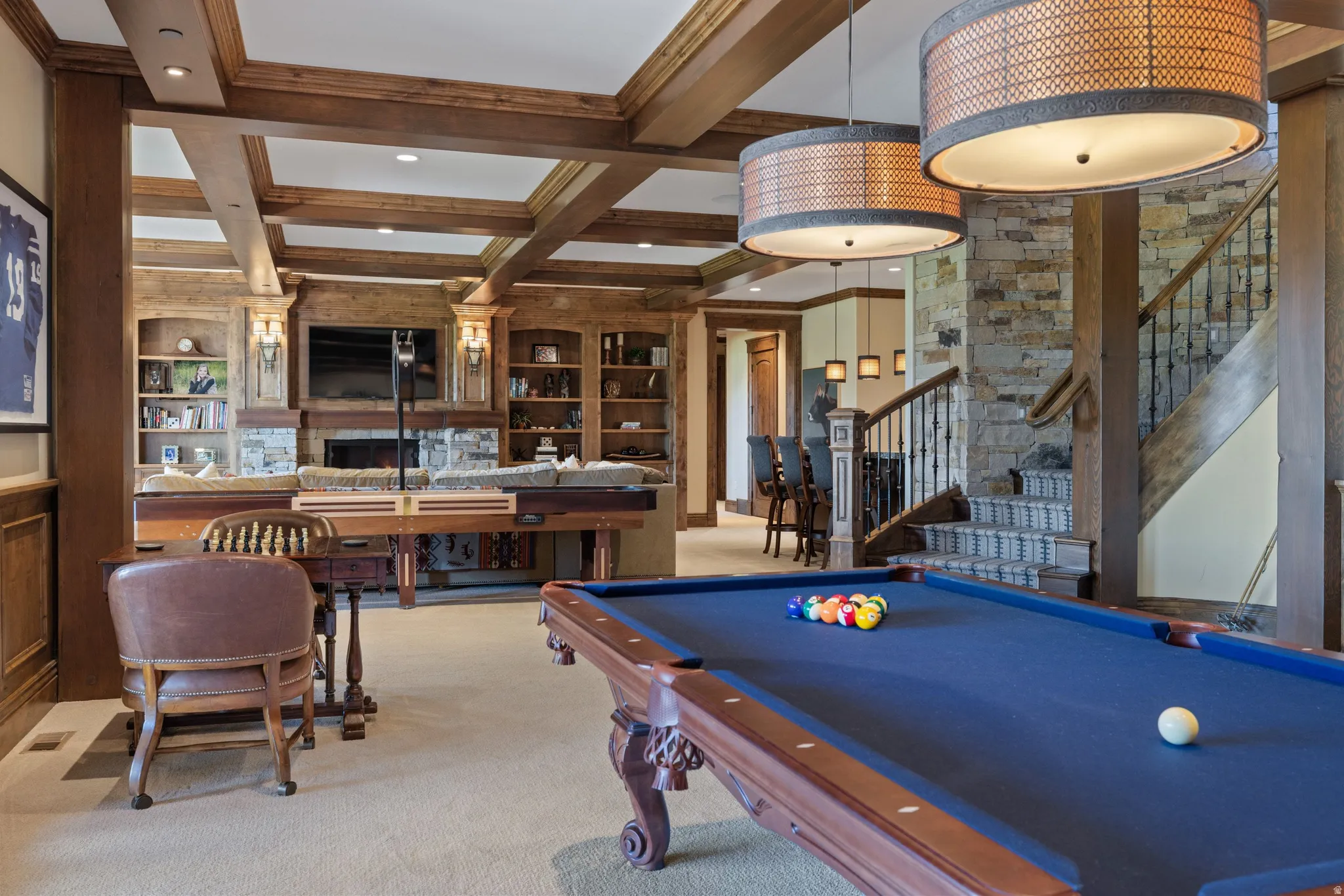 Open recreation space featuring a built-in entertainment center with a stone fireplace, wood beams, and recessed lighting
