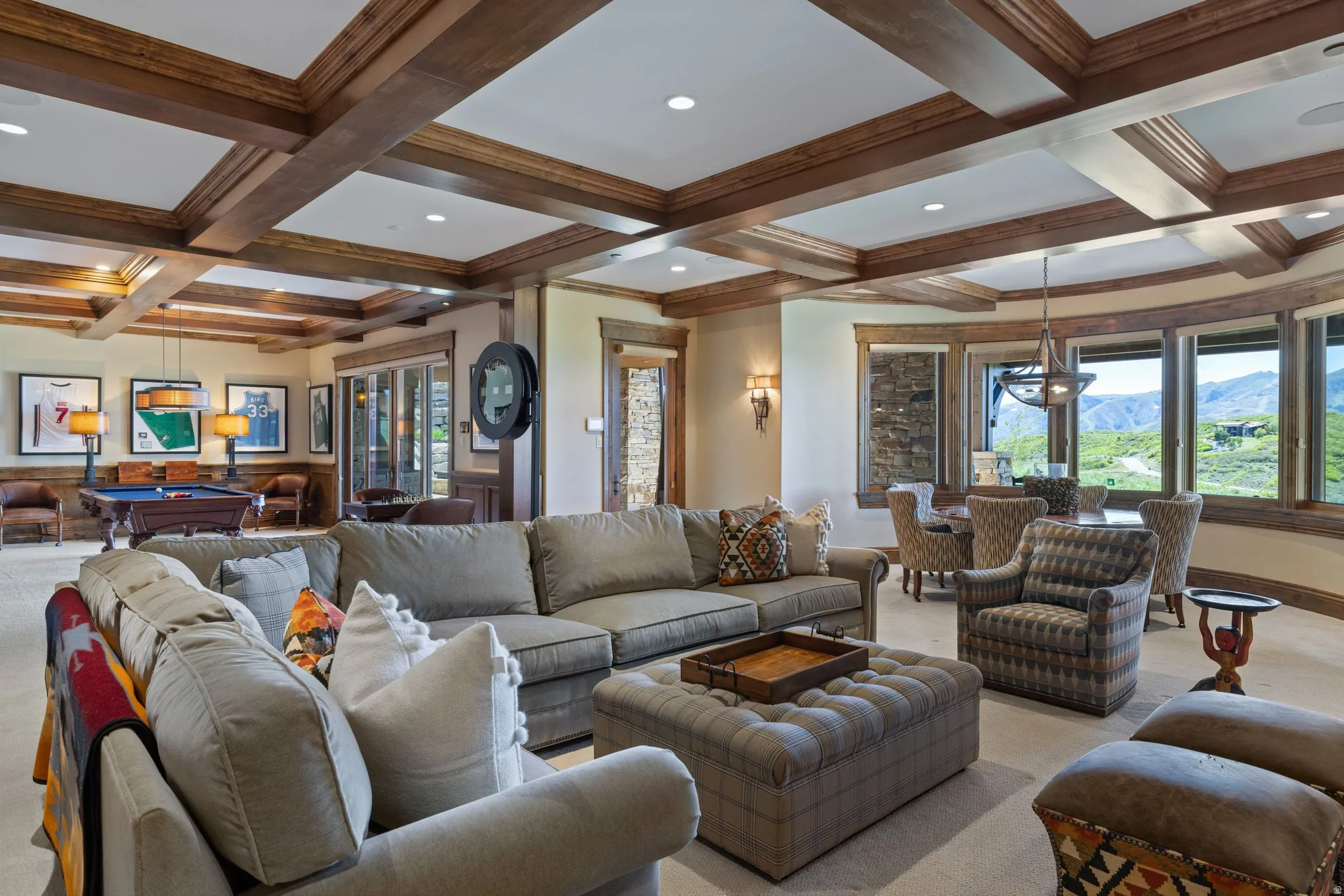 Spacious living area featuring coffered ceilings with exposed wood beams, a dedicated dining area with large windows, and a separate billiards space