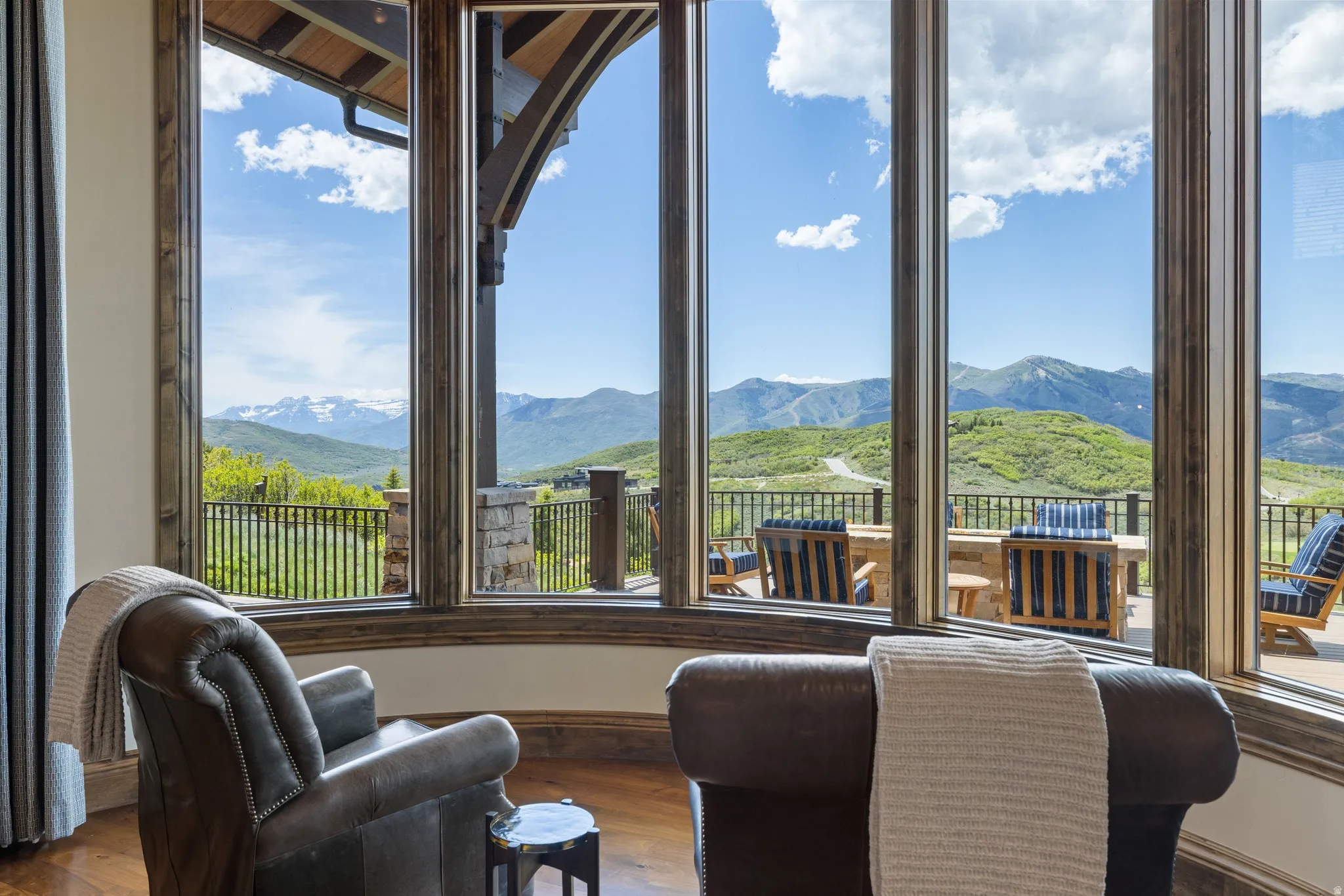 Expansive floor-to-ceiling windows with wood-finish trim, showcasing mountain scenery and a stone patio