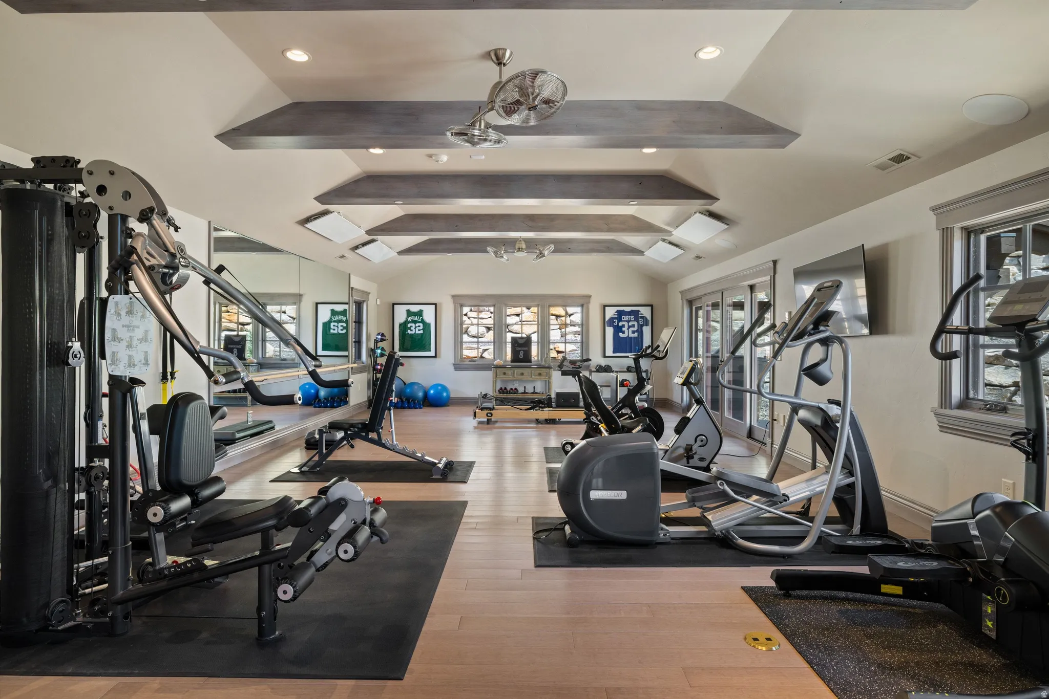 Dedicated fitness space featuring wood-finish flooring, recessed lighting, and tray ceilings with exposed wood beams
