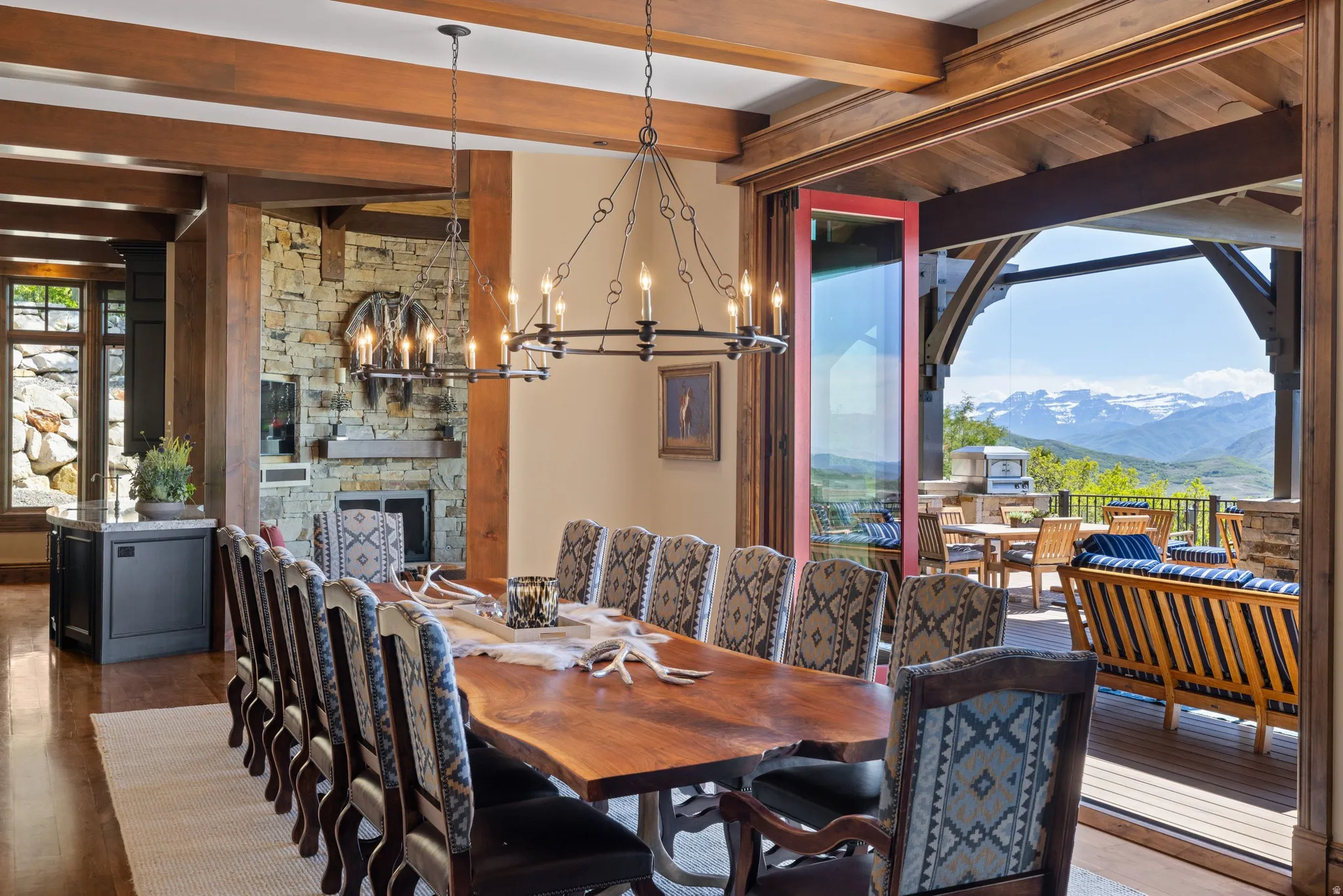 Dining area featuring exposed wood beams, a stone fireplace, and wood-finish flooring