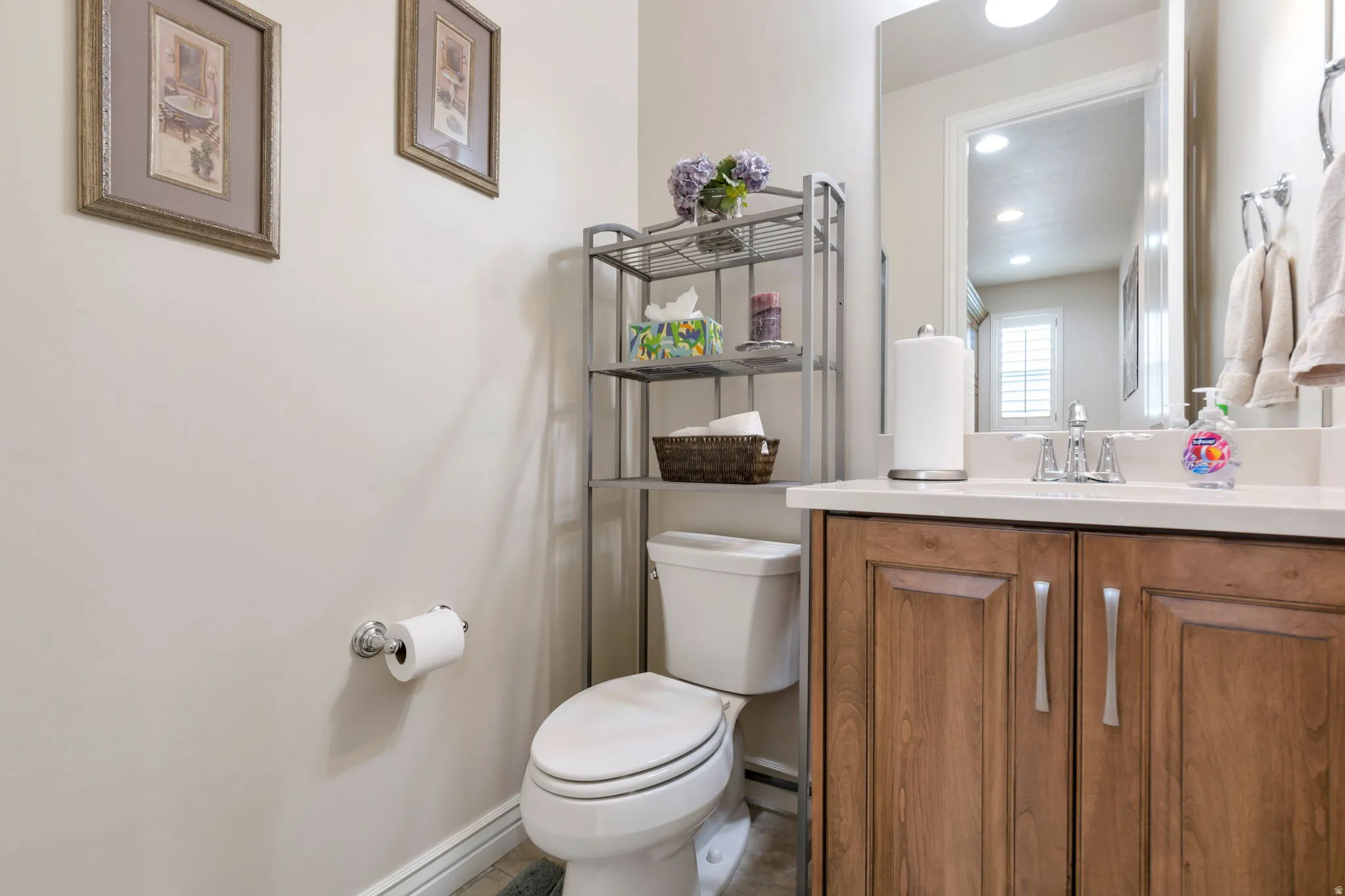 Bathroom featuring a light wood-finish vanity with panel detailing, a white countertop, and a rectangular mirror