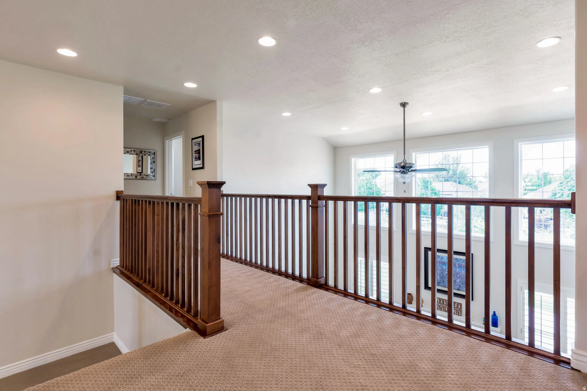 Upper-level hallway with wood railing and carpet flooring