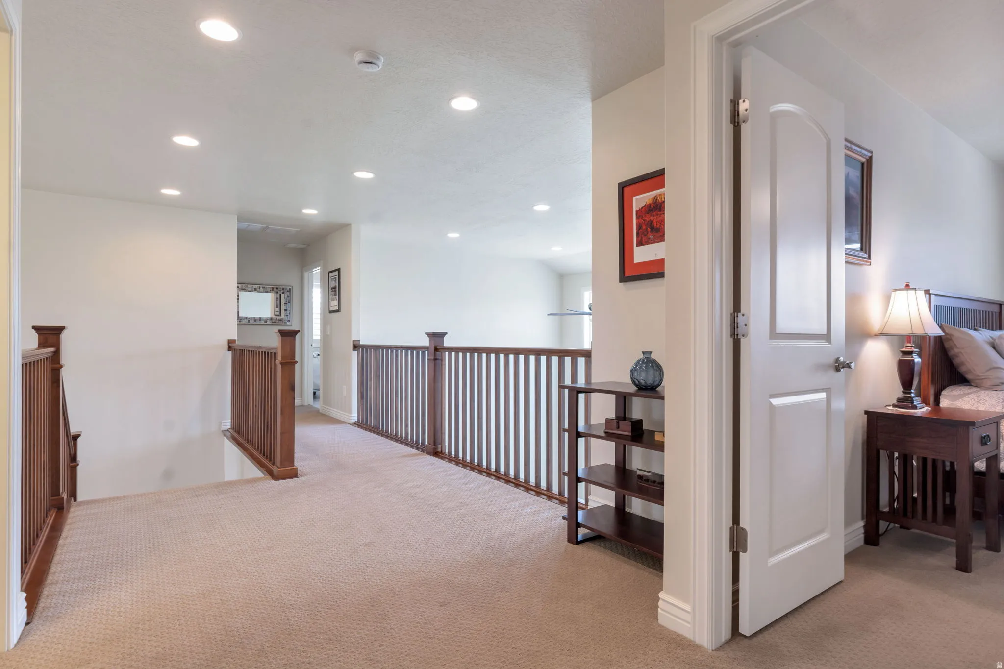 Carpeted upper-level hallway featuring recessed lighting and wood balustrade
