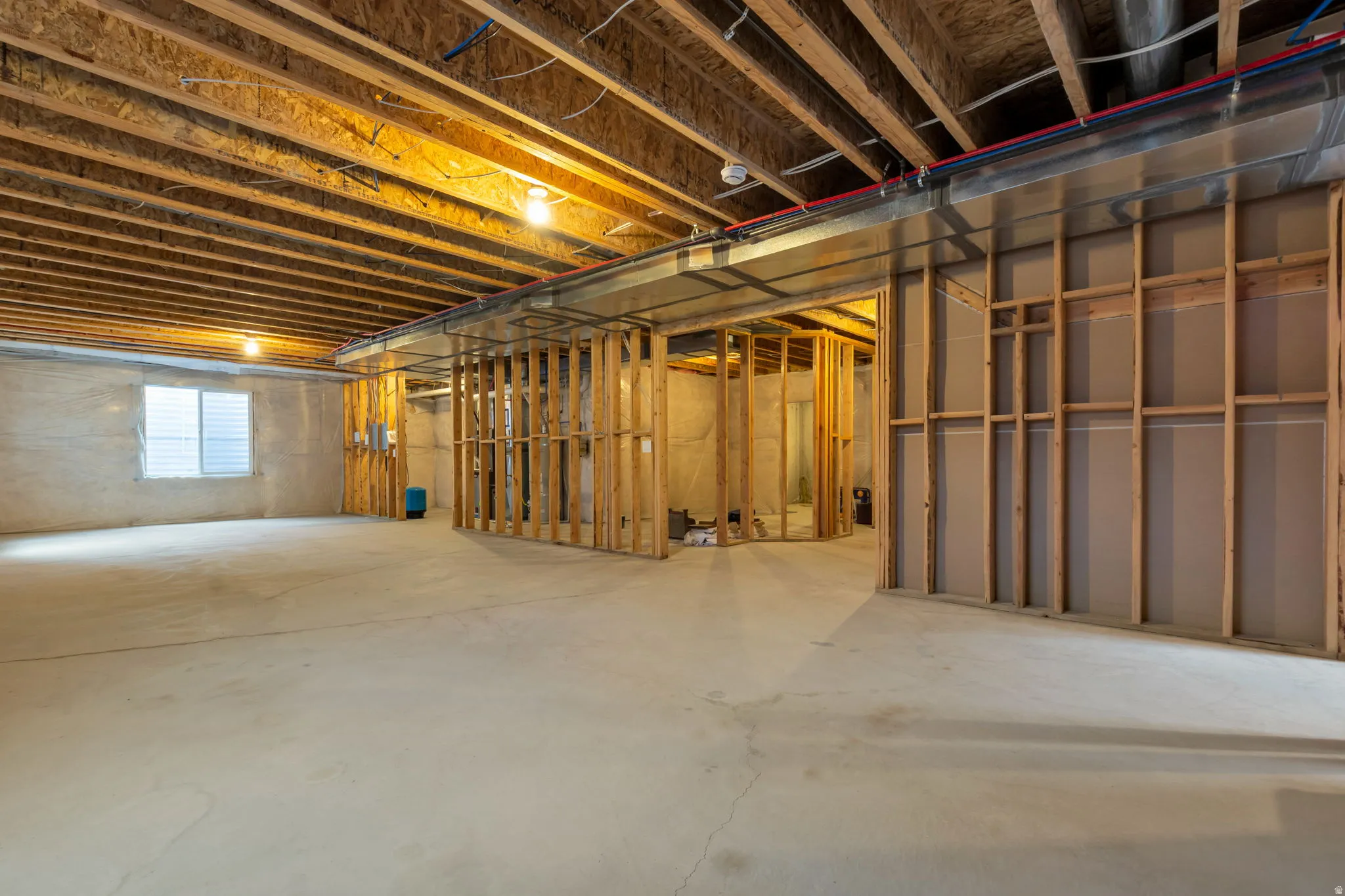 Unfinished lower level featuring exposed wood joists, concrete flooring, and framed interior walls