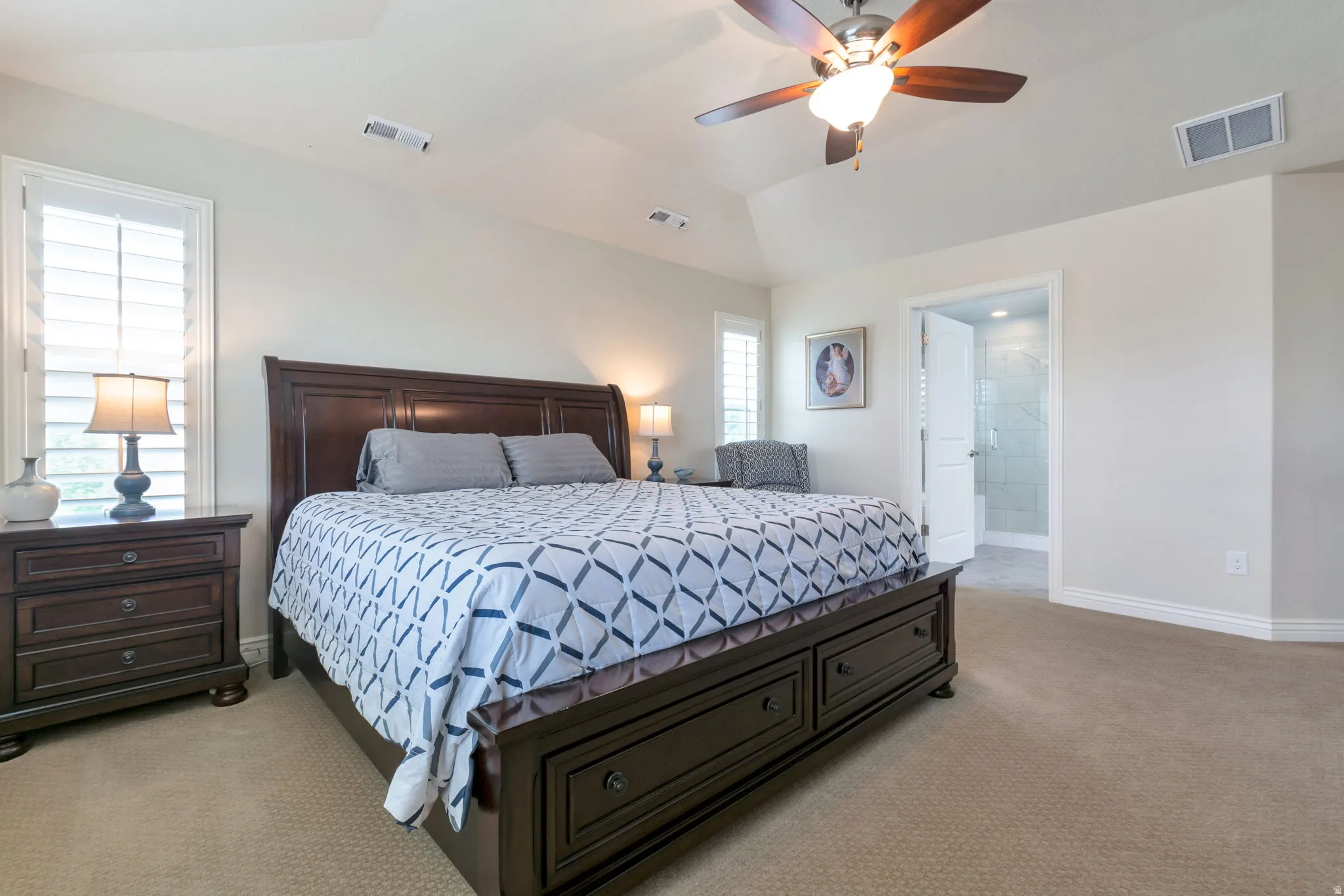 Carpeted bedroom with a vaulted ceiling and a ceiling fan
