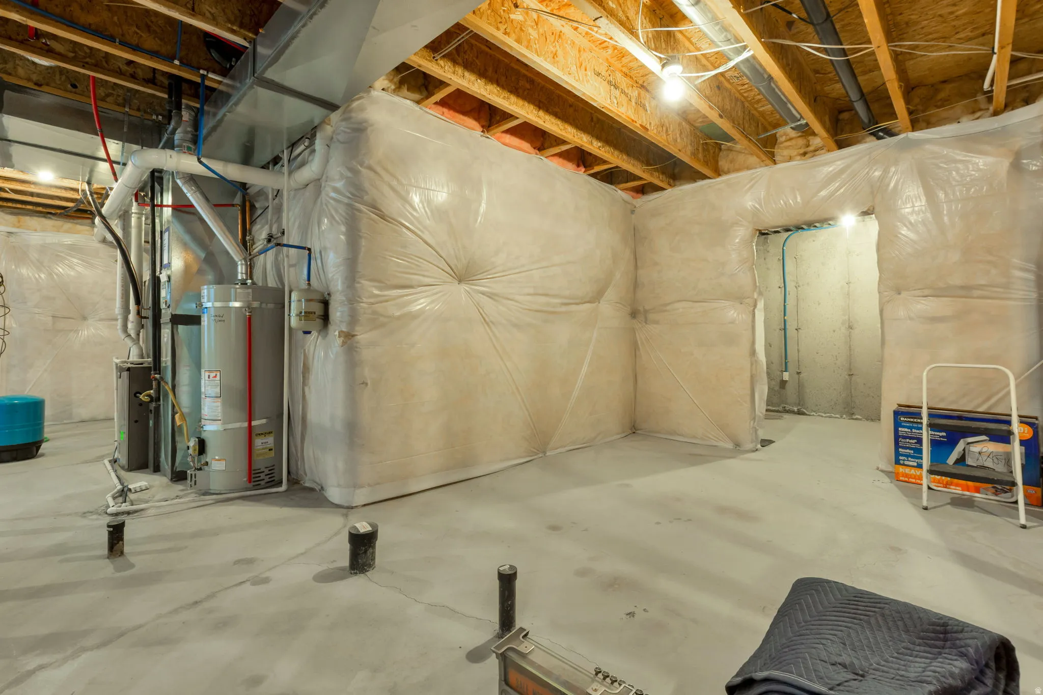 Unfinished basement featuring exposed wood joists, concrete flooring, and insulated perimeter walls