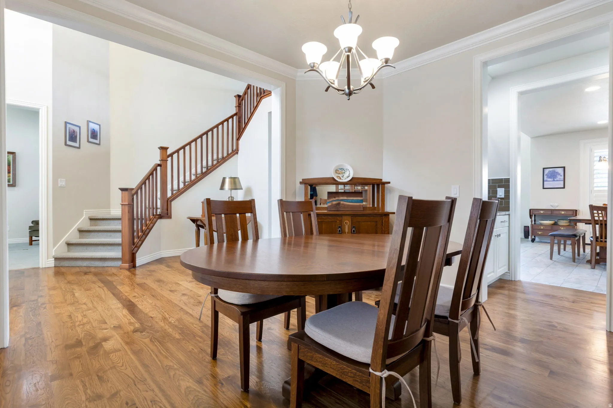 Expansive dining area featuring wood-finish flooring, a decorative chandelier, and crown molding