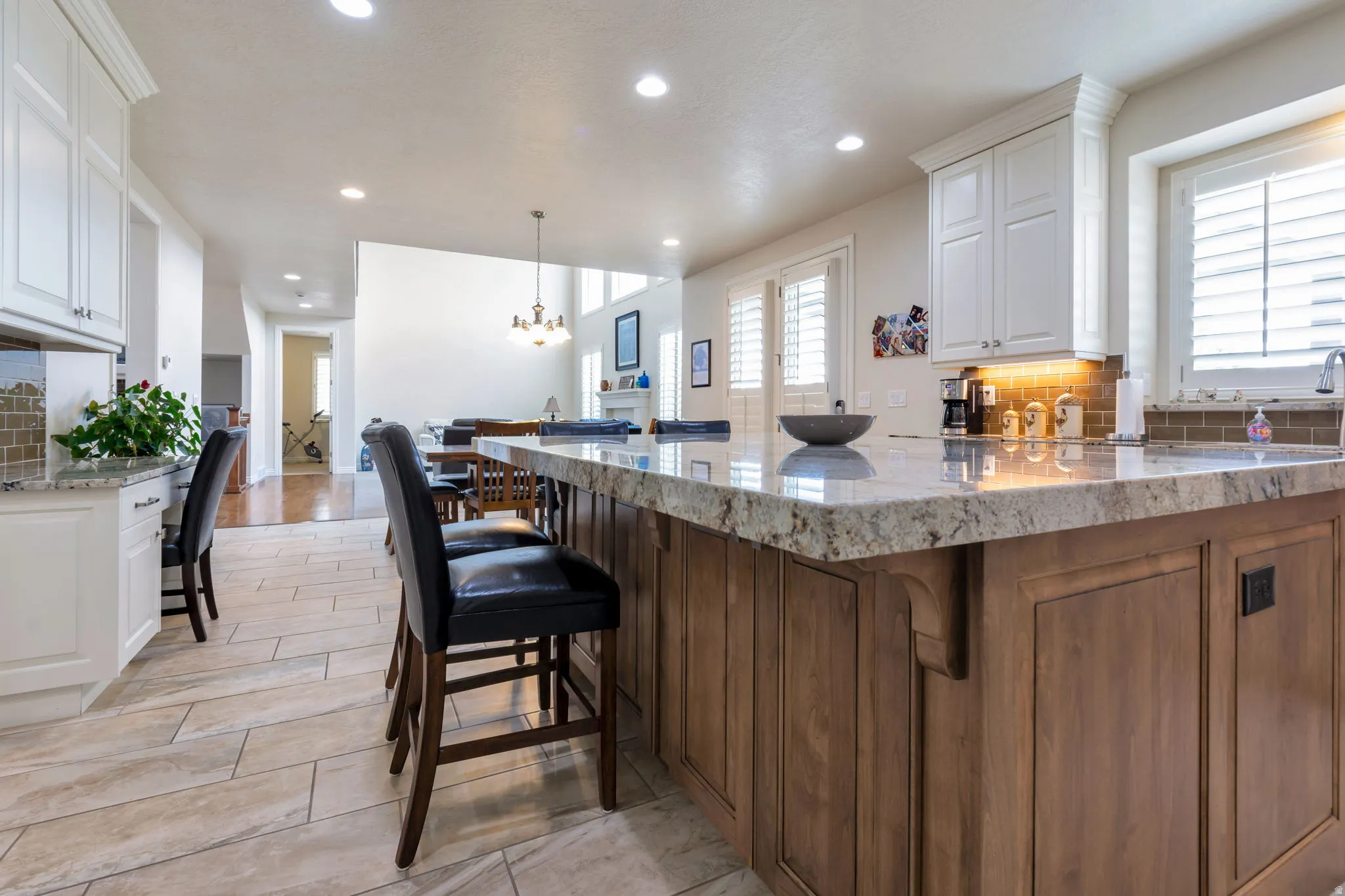 Kitchen featuring an expansive island with a light-toned countertop, wood-finish cabinetry, and built-in seating