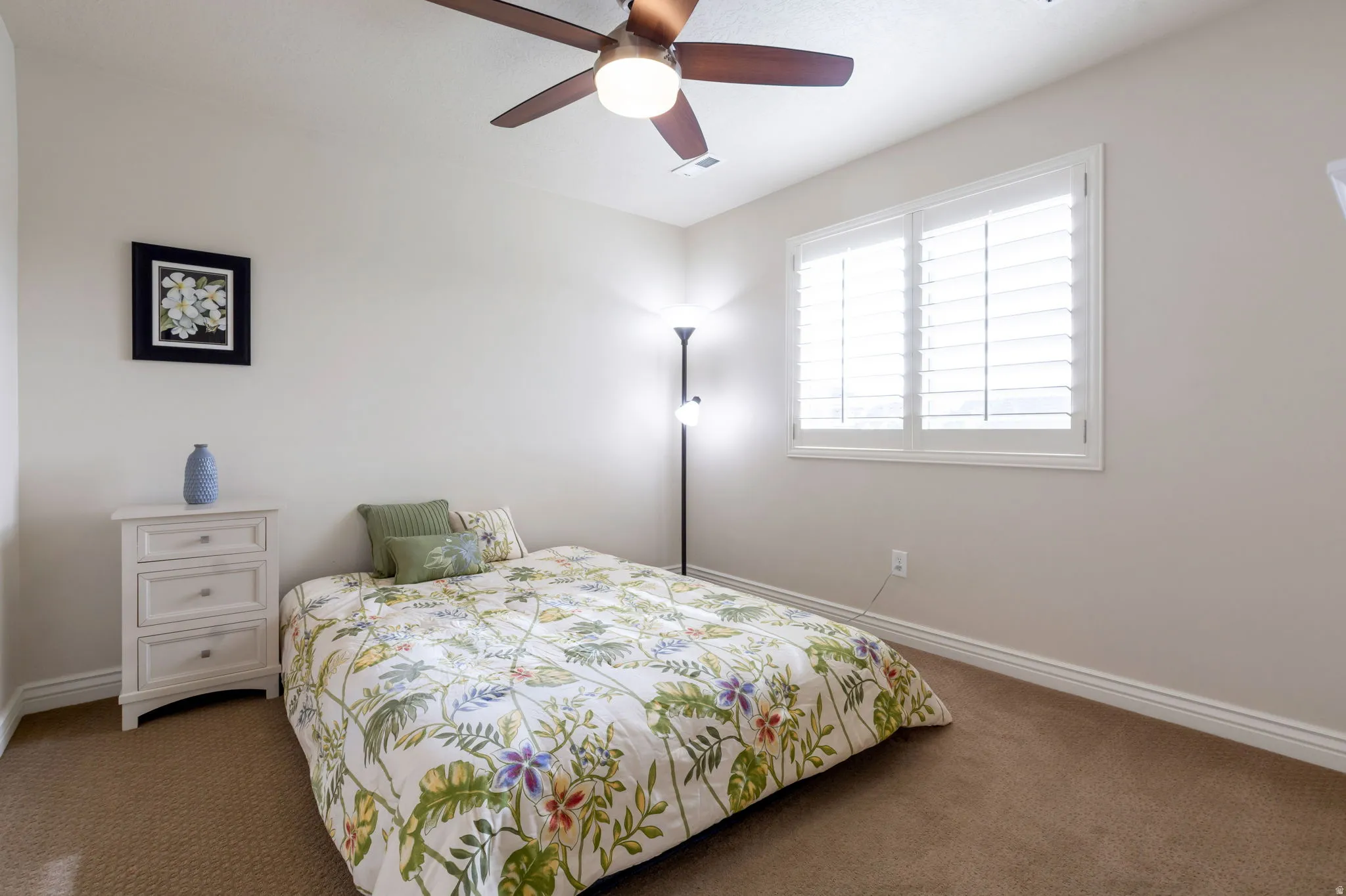 Carpeted room featuring a ceiling fan with integrated lighting, a window with white plantation shutters, and light-toned wall paint