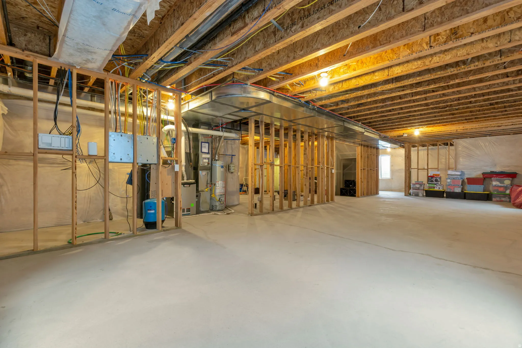 Unfinished basement featuring exposed wood joists, concrete flooring, framed wall sections, and visible HVAC ductwork