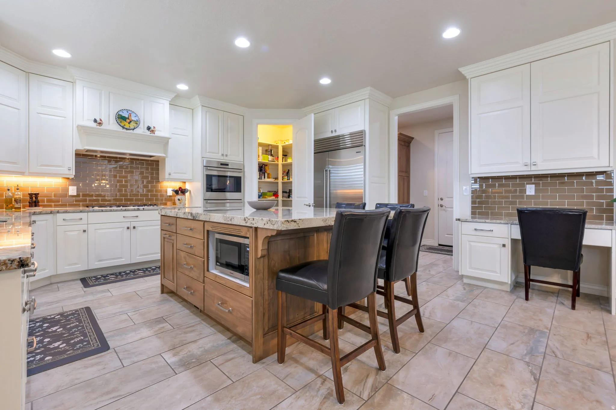 Spacious kitchen featuring an expansive center island with seating, integrated microwave, and granite countertop