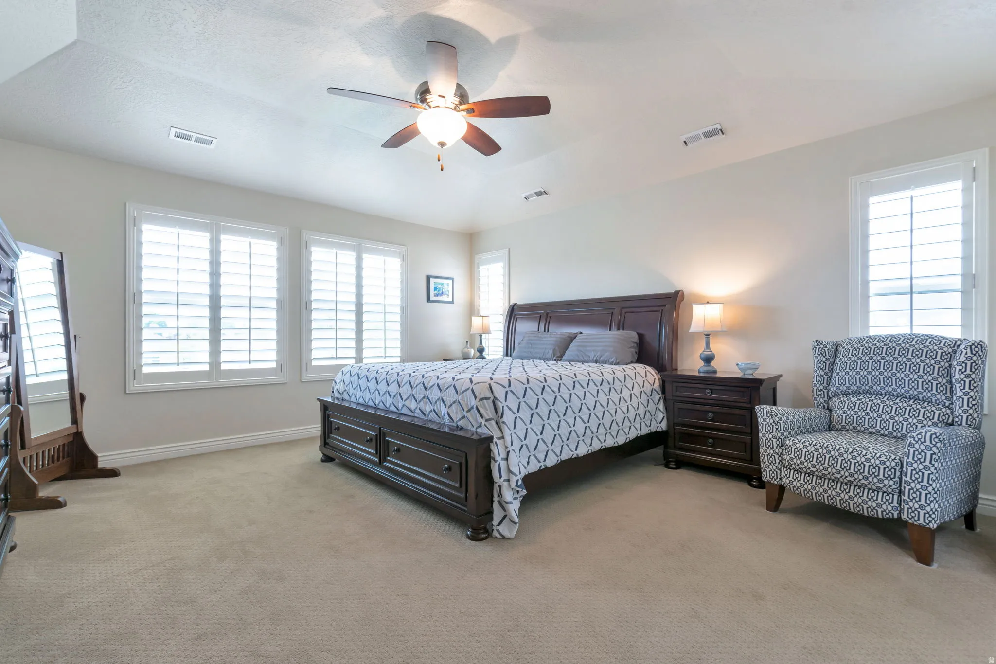 Carpeted room featuring multiple windows with plantation shutters, a ceiling fan with integrated lighting, and crown molding