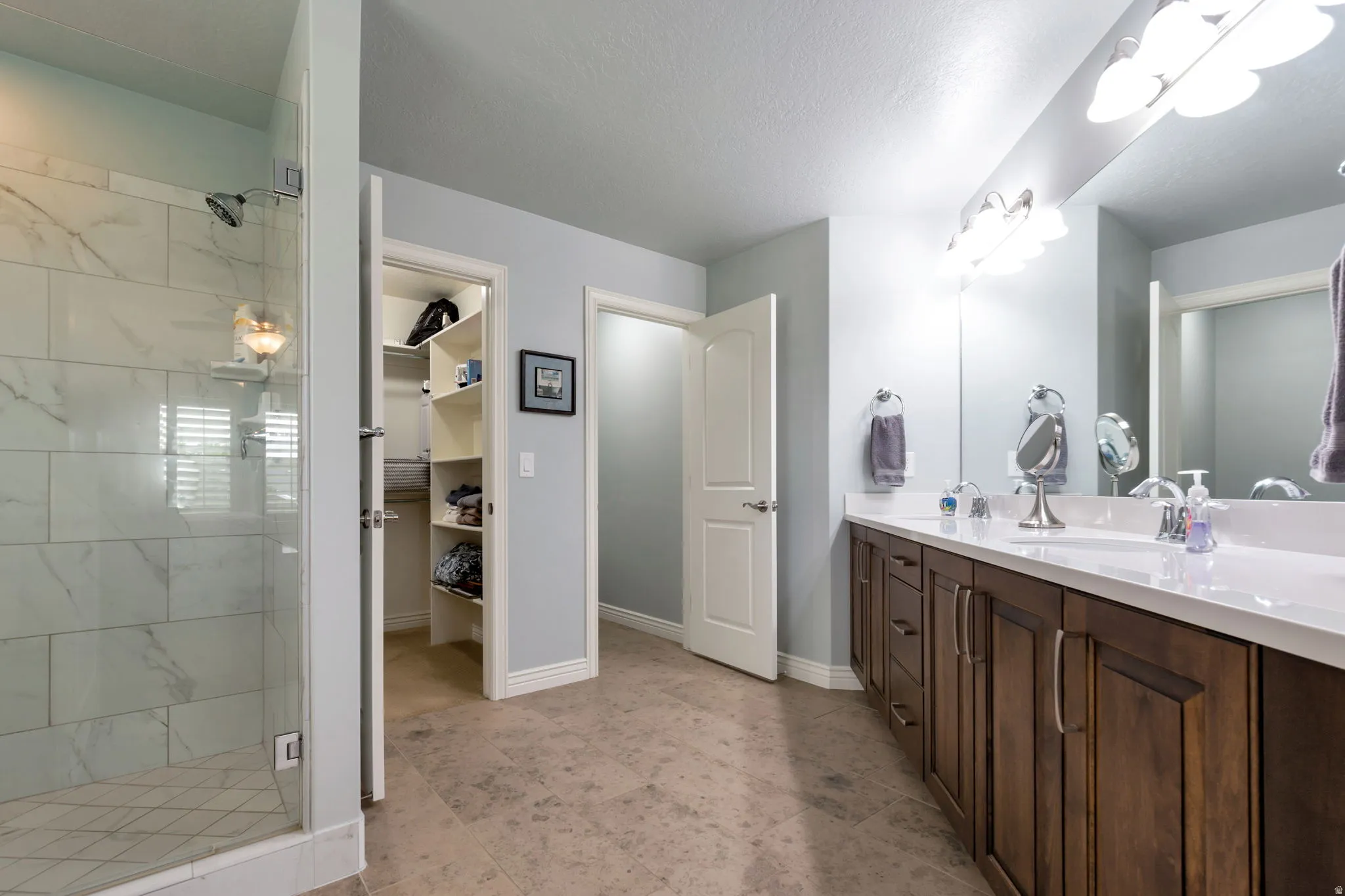 Bathroom featuring a dual vanity with dark wood cabinetry, a white countertop, and individual sinks