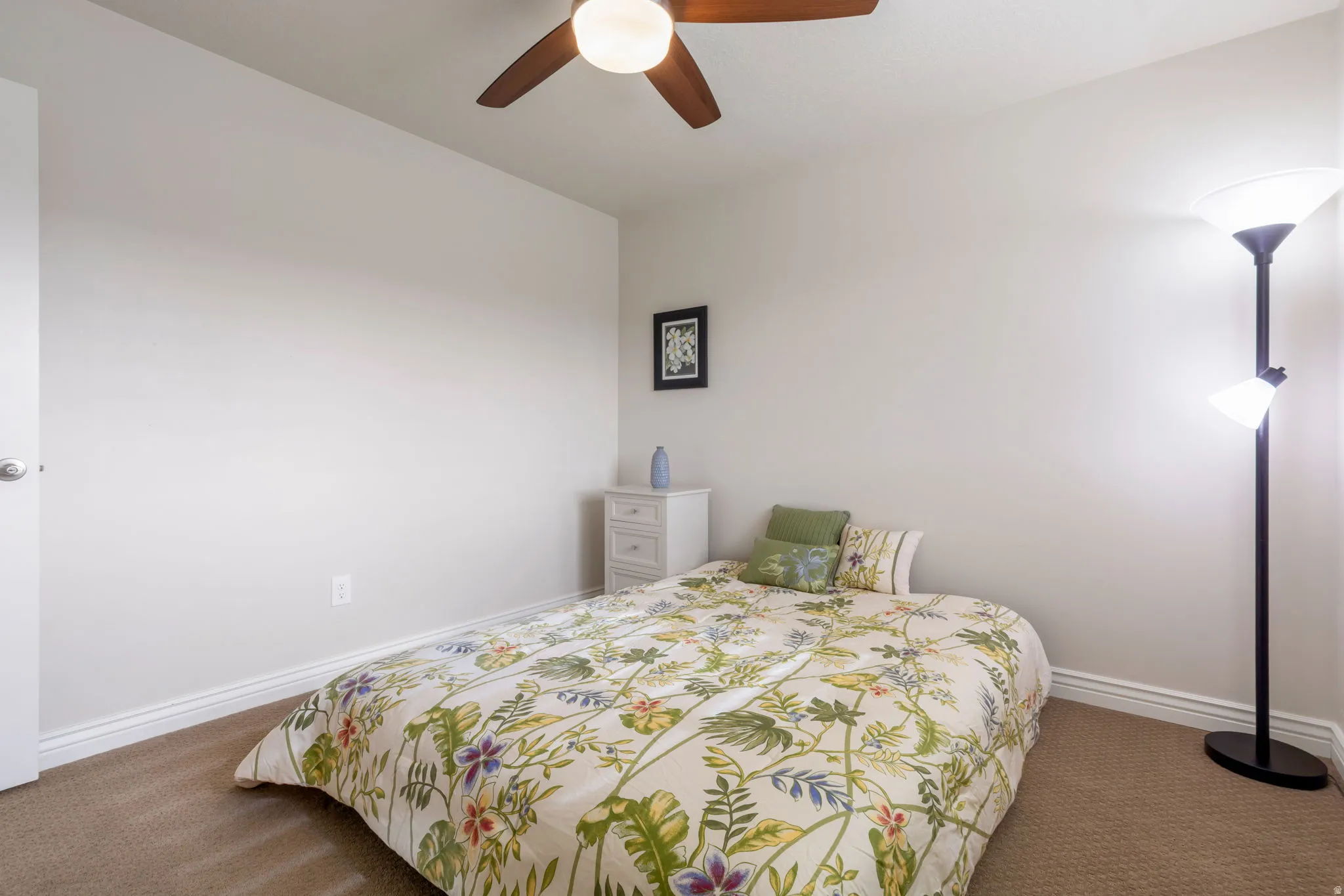 Neutral-toned room featuring a ceiling fan with integrated lighting, a white door with a round knob, and plush carpet flooring