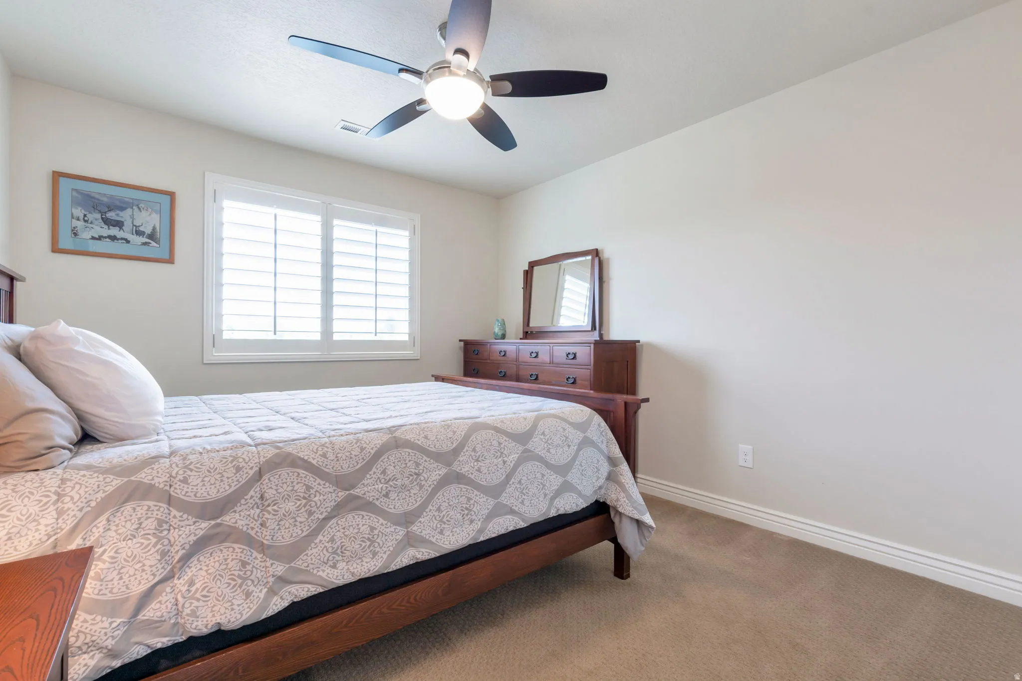 Carpeted room featuring a ceiling fan with integrated lighting, a window with white plantation shutters, and light-toned walls with triple-layer baseboard molding