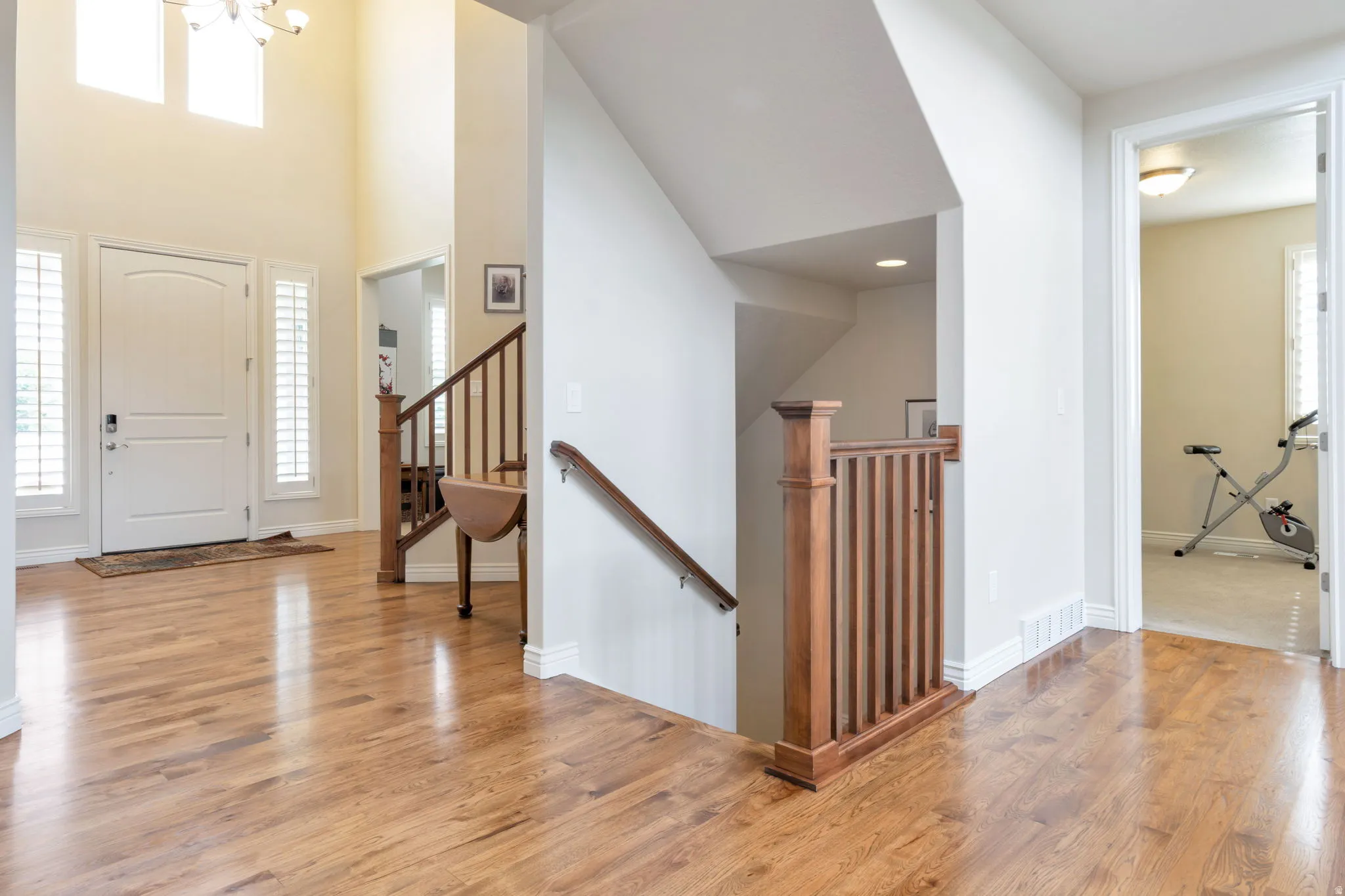 Grand foyer featuring a high ceiling, wood-finish flooring, a contemporary chandelier, a staircase with wood railing, and an arched entryway