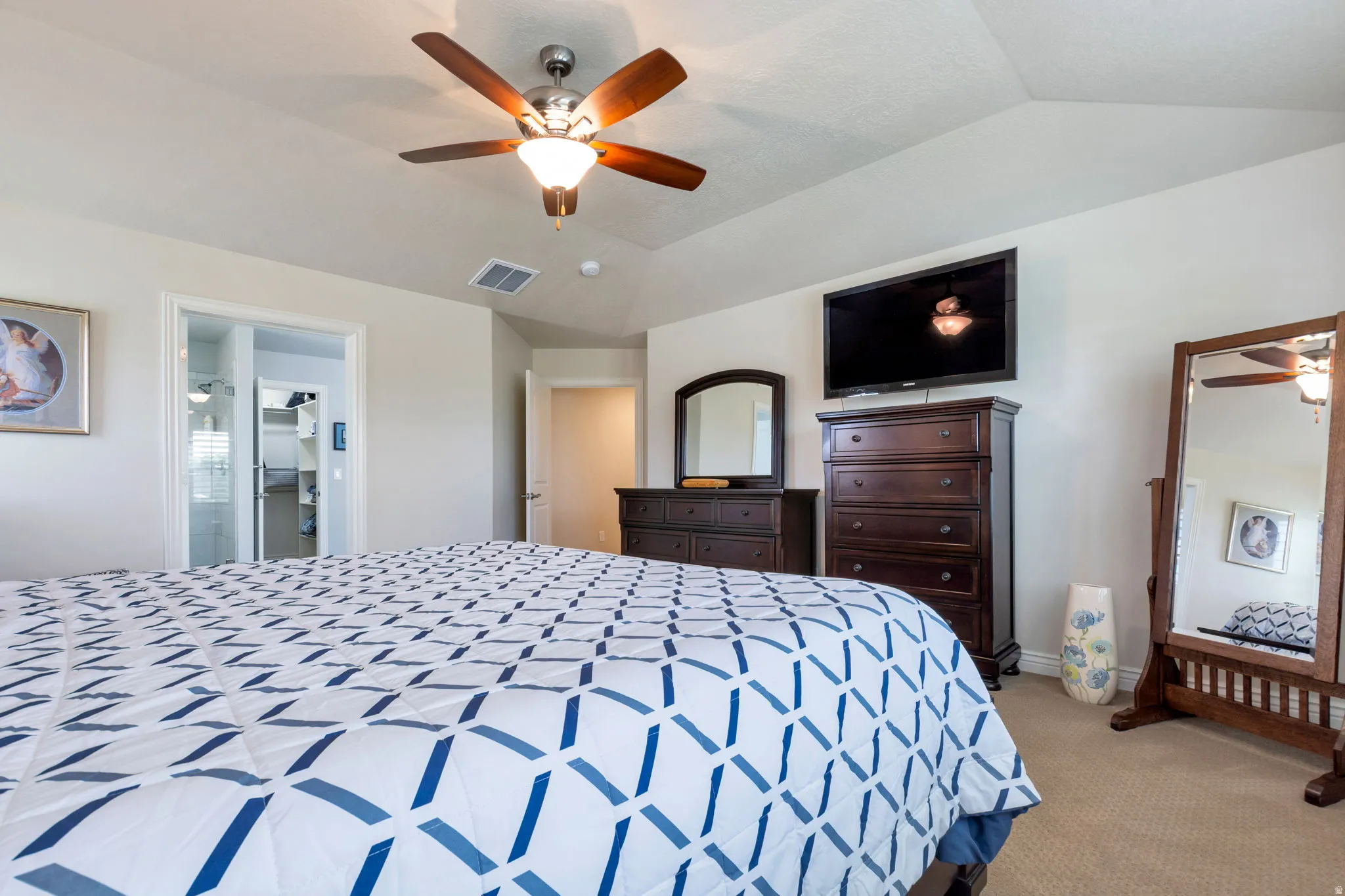 Spacious bedroom featuring vaulted ceilings, a ceiling fan with integrated lighting, and carpet flooring