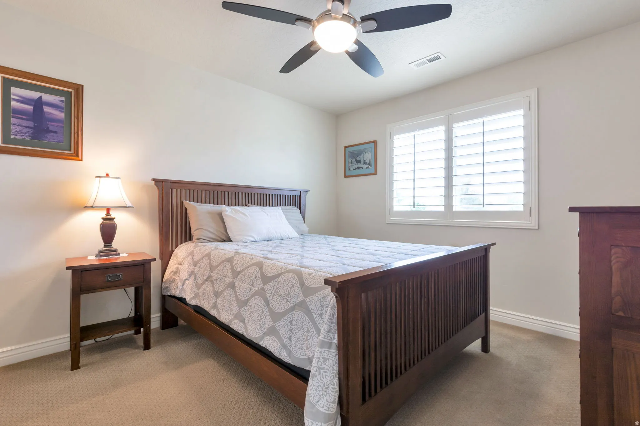 Interior room featuring neutral wall paint, carpet flooring, a ceiling fan with integrated lighting, and a window with white plantation shutters