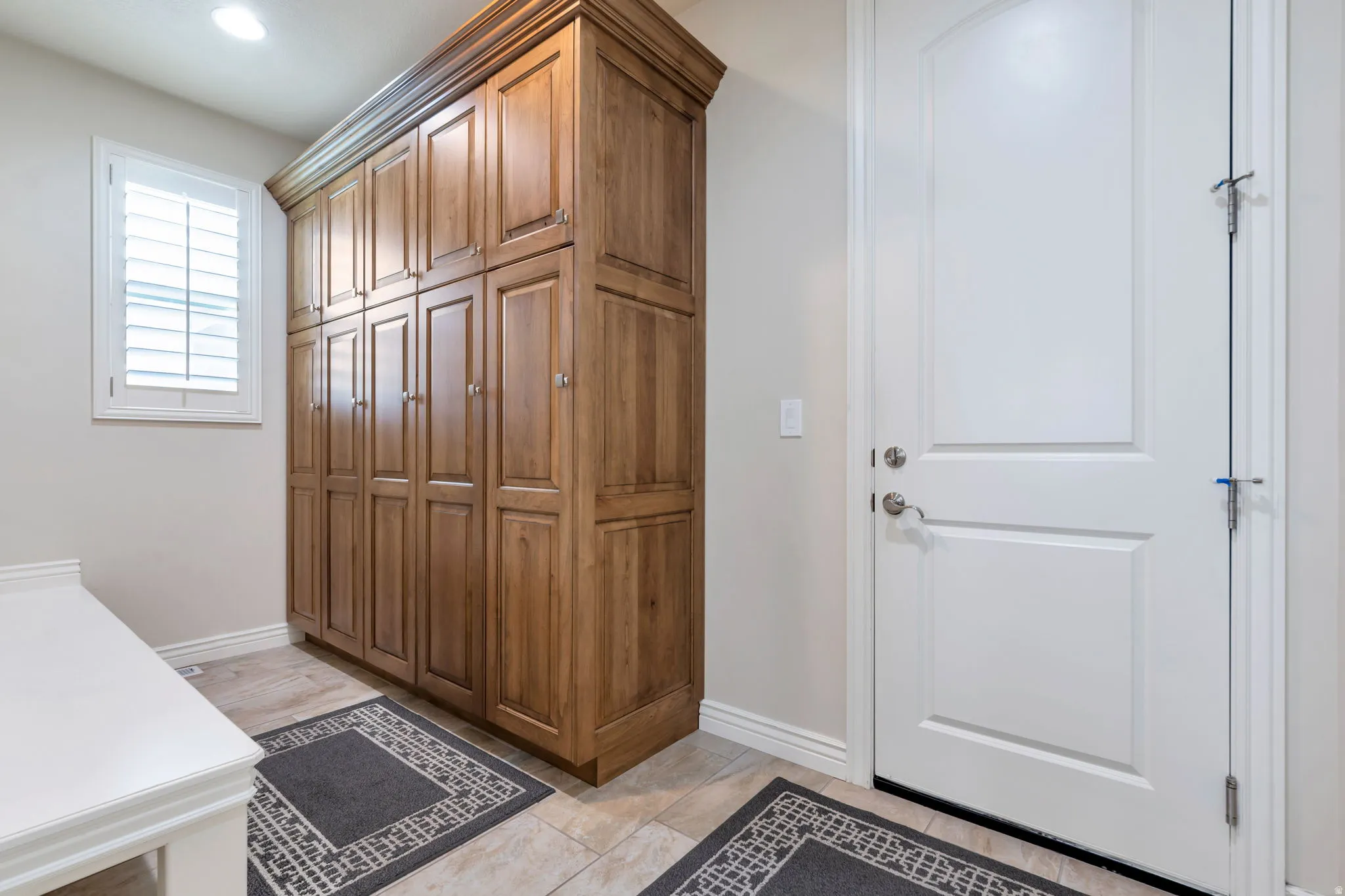 Built-in wood cabinetry offering extensive storage, complemented by light-toned tile flooring