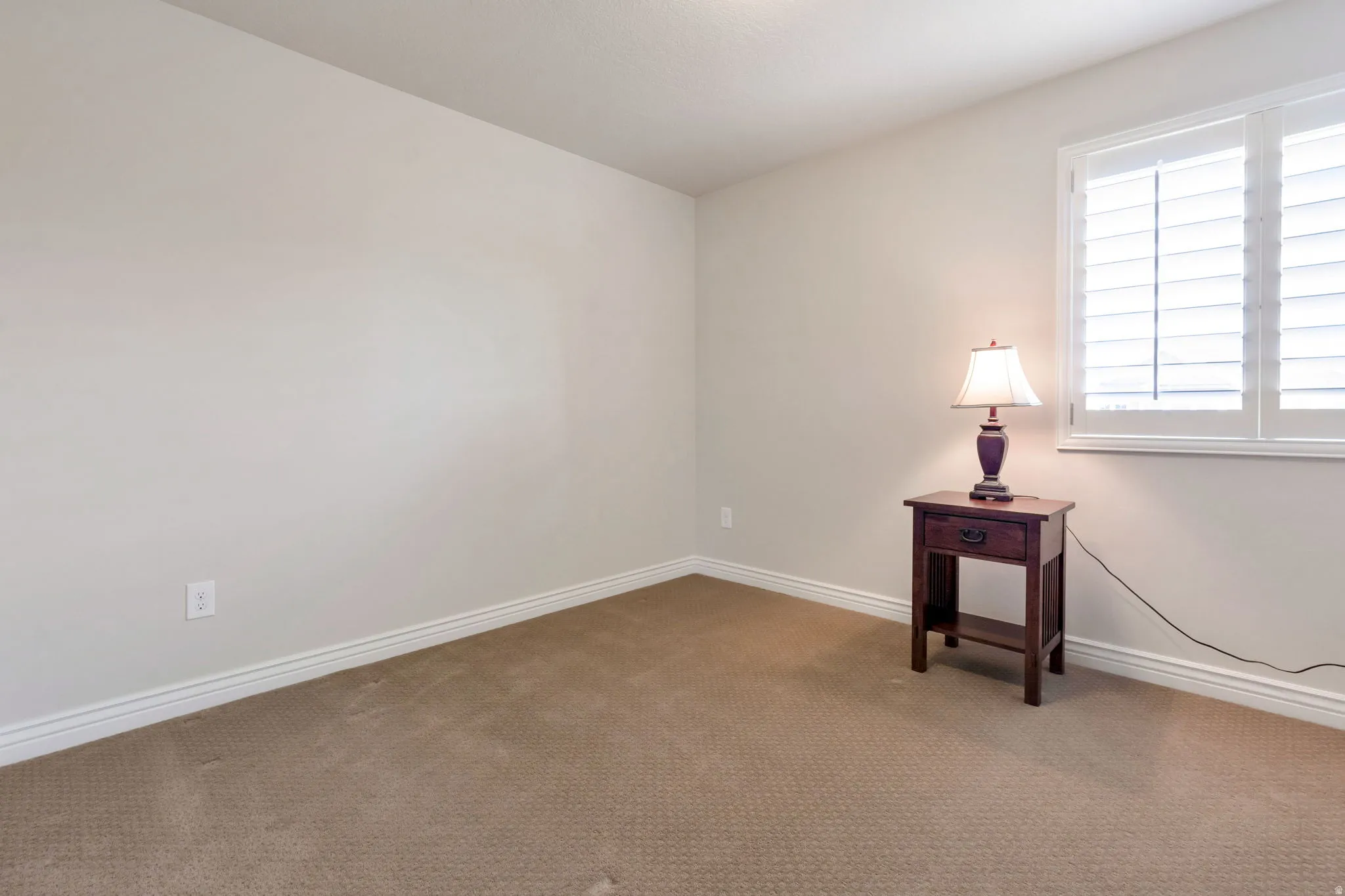 Neutral-toned carpeting and walls complement white trim and window shutters
