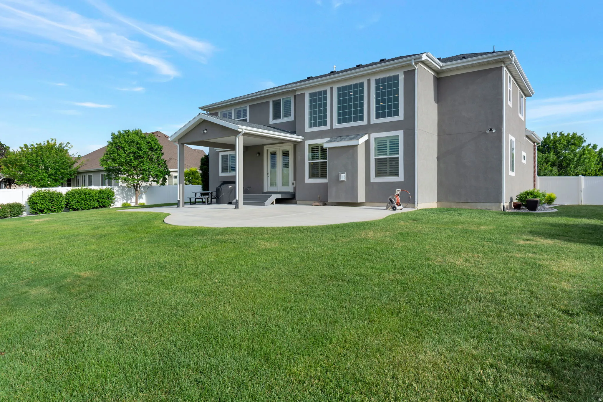 Expansive green lawn with a white privacy fence